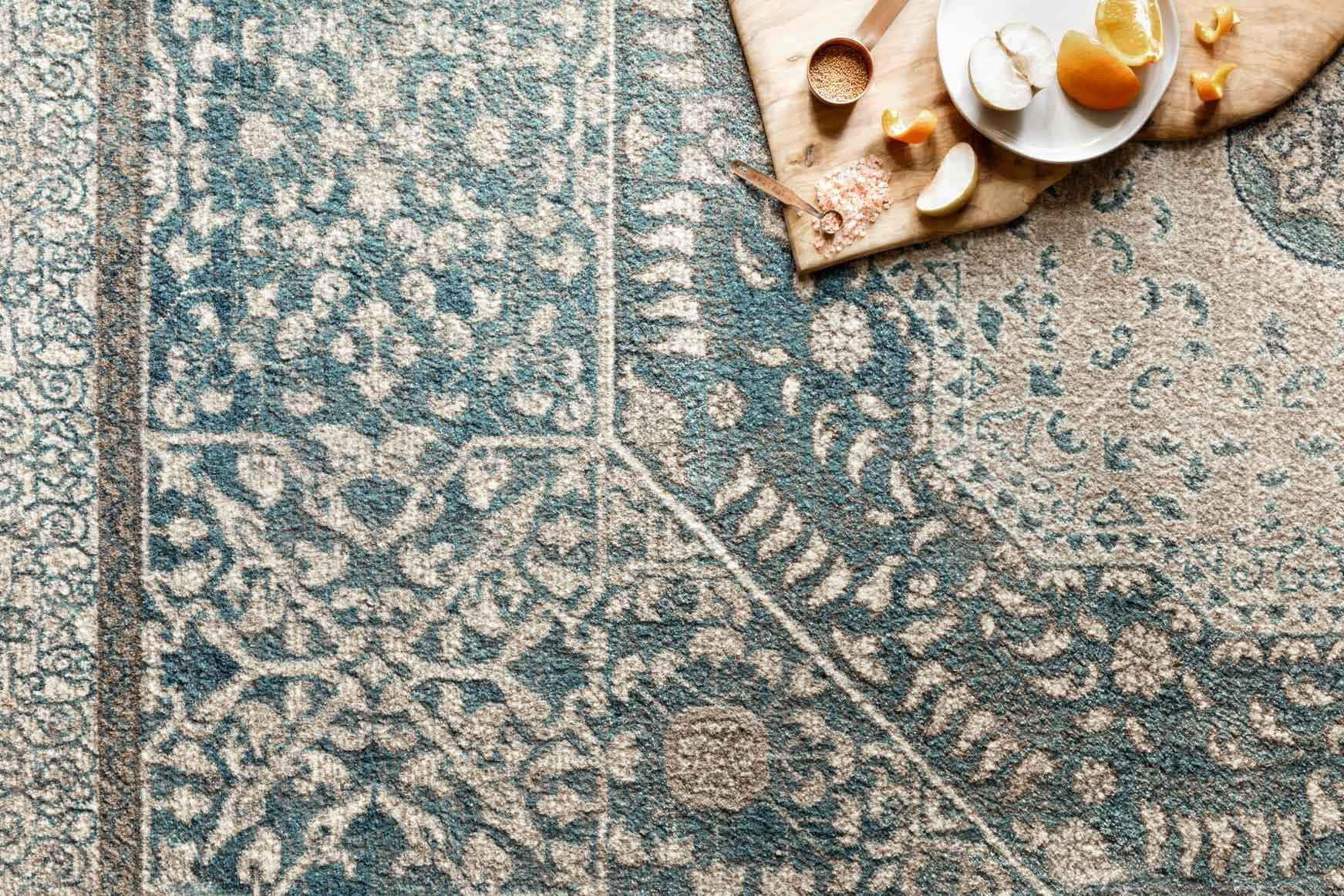 Close-up of blue and sand rug with distressed floral and geometric motifs