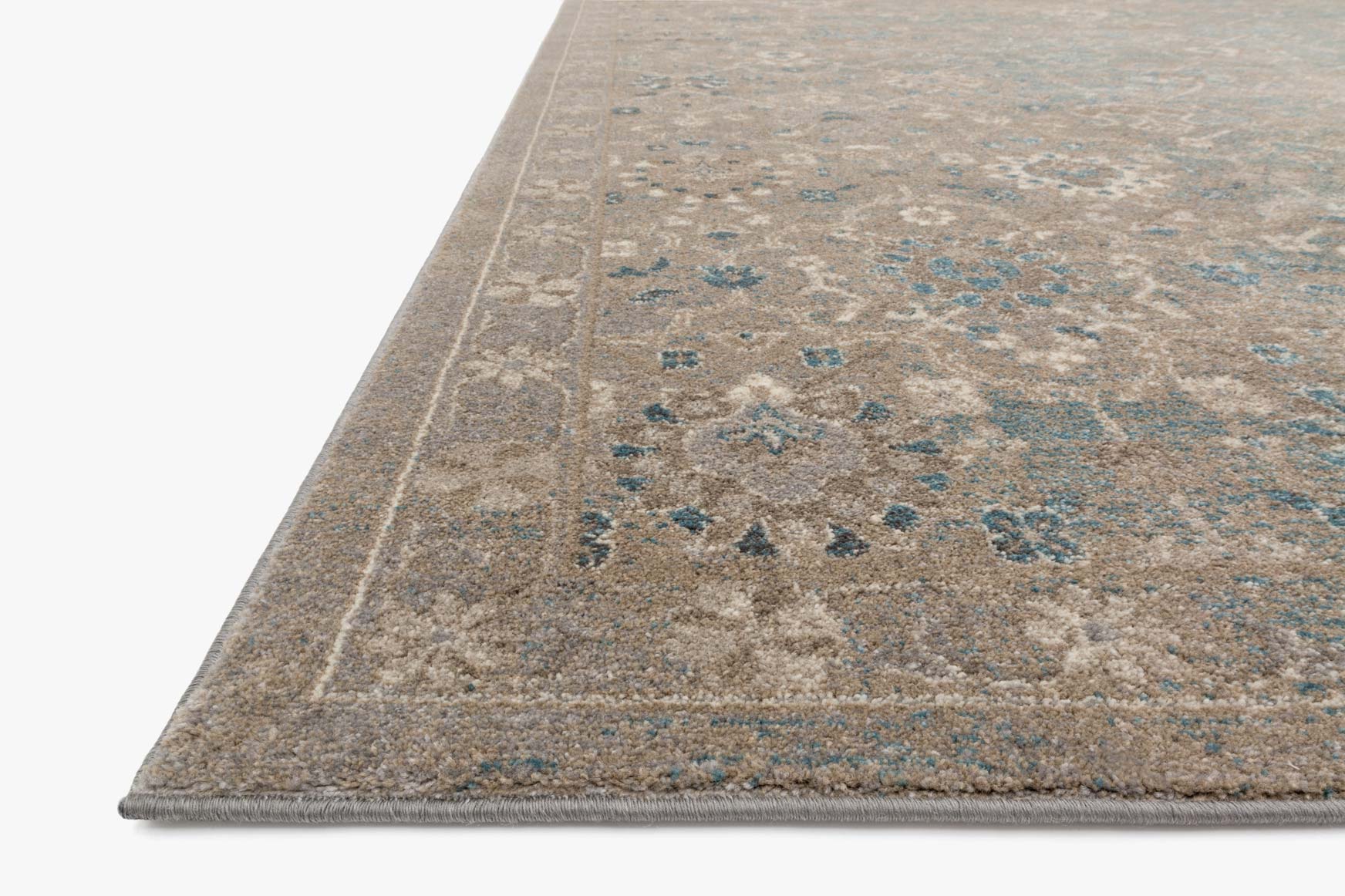 Power-loomed area rug border detail, blue-gray motifs on heathered beige ground