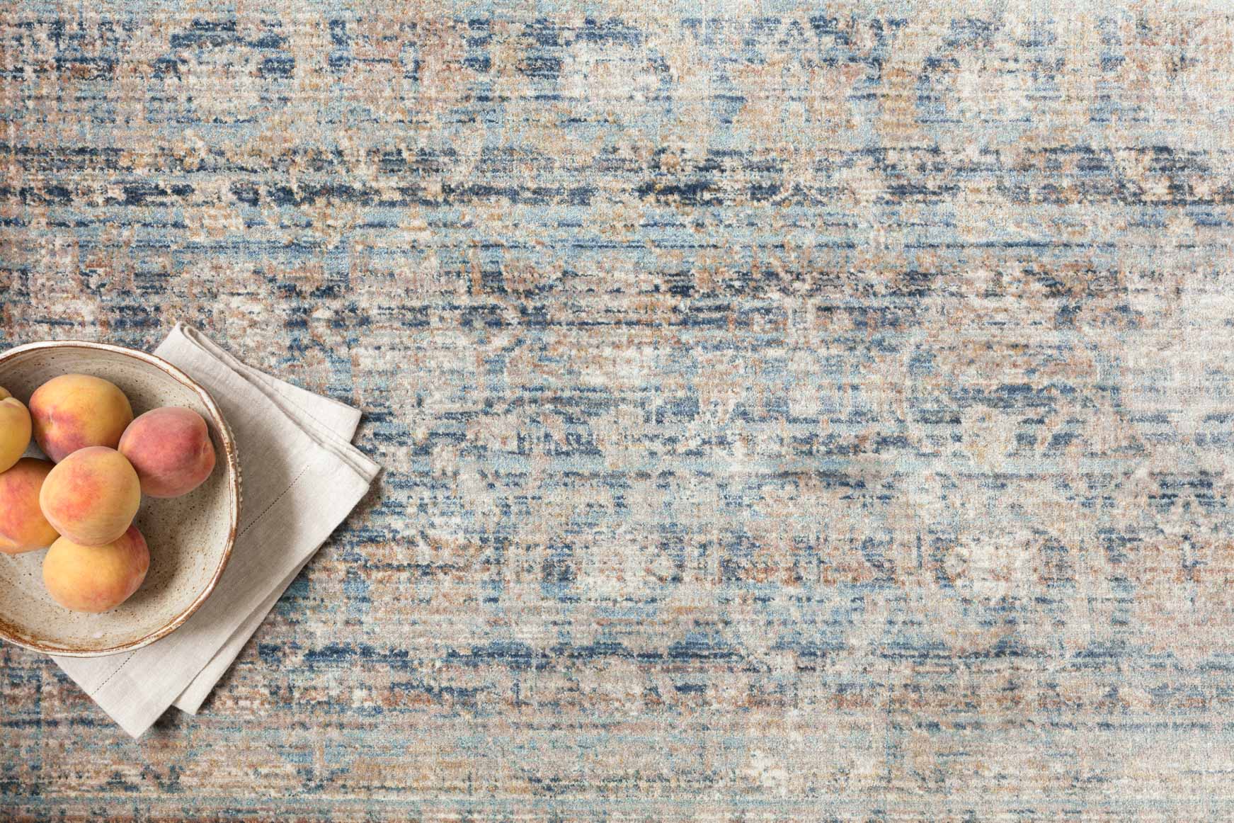 Traditional power-loomed rug close-up in ocean blue and gold with textured abstract pattern