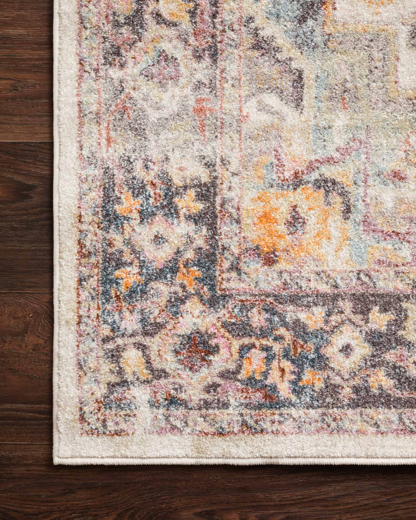 Ivory rug edge with dense multicolor distressed motif and charcoal accents.