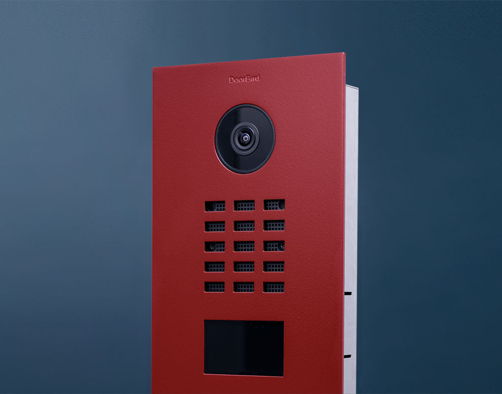 Flame red DoorBird video door station front with camera and call button array, side edge visible