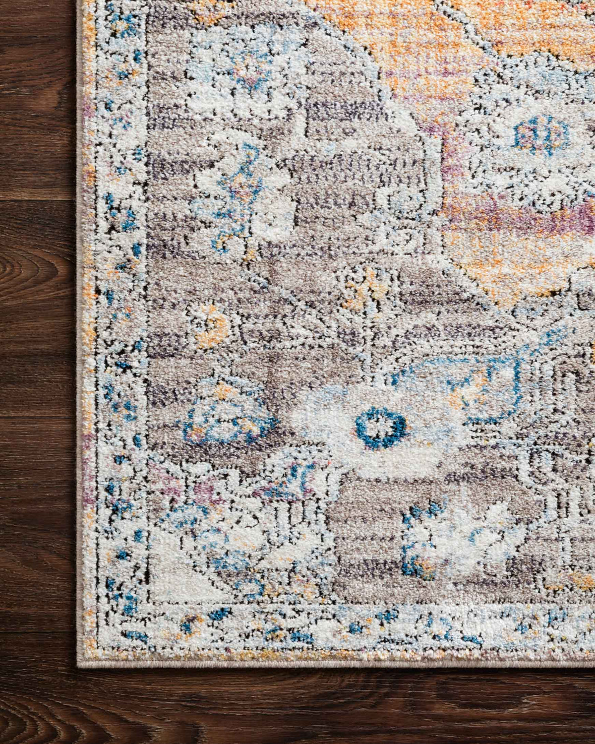 Textured close-up of rug surface with light gray base and blue-orange distressed pattern