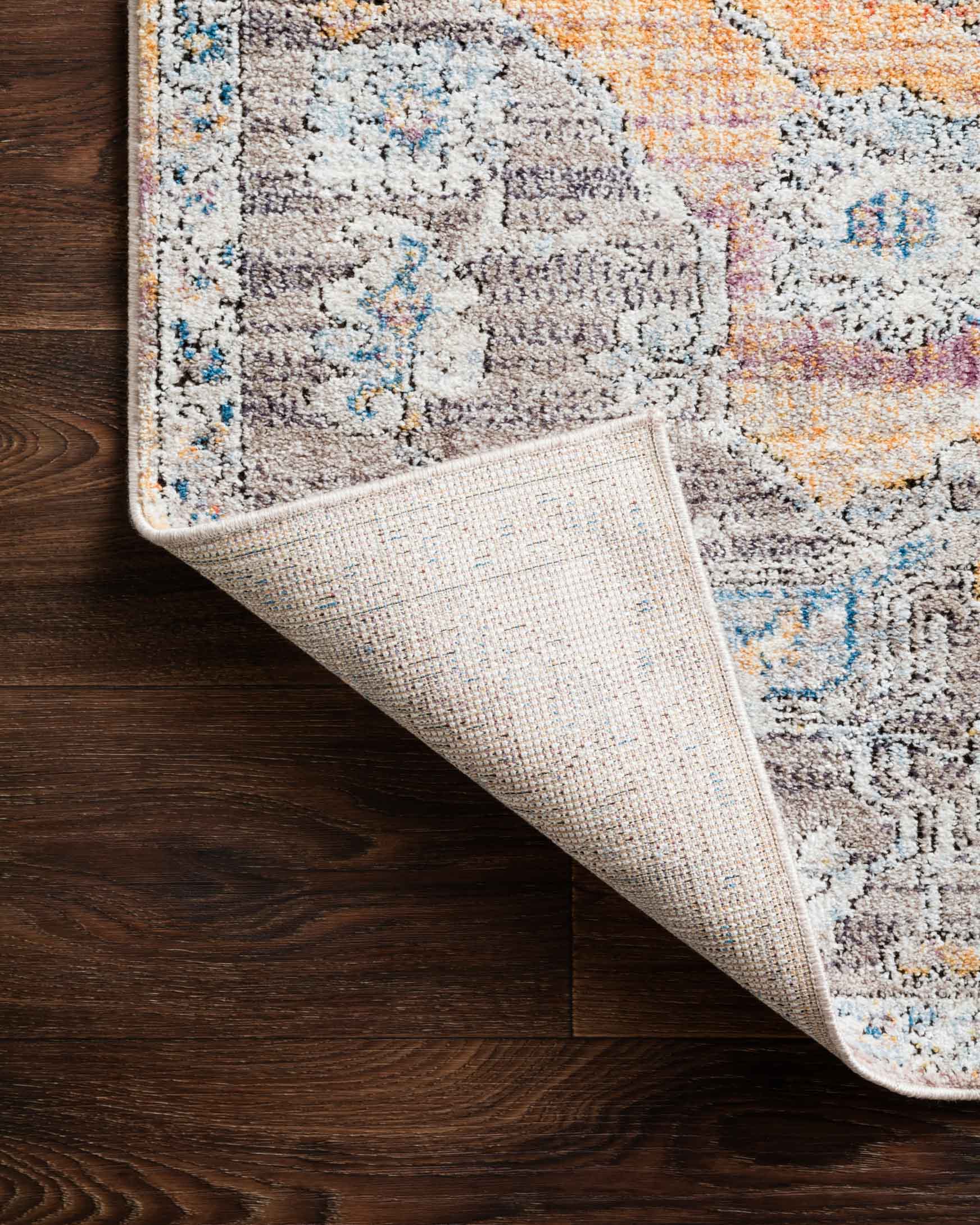 Folded edge of abstract rug showing woven texture on light gray, beige, blue, and orange colors