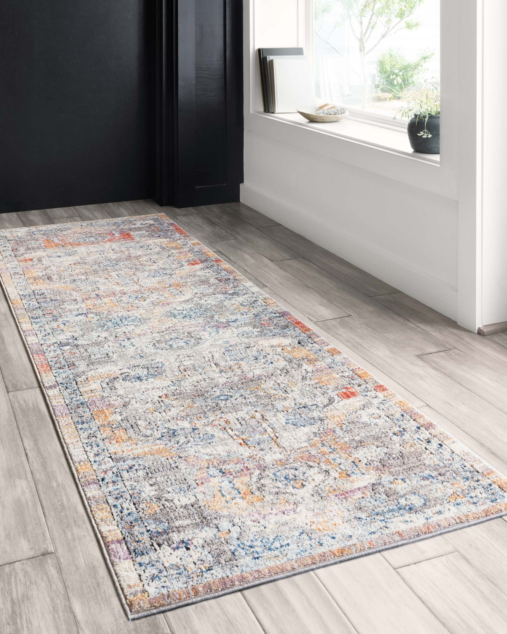 Runner-style abstract rug with light gray ground, blue motifs, and orange border detail