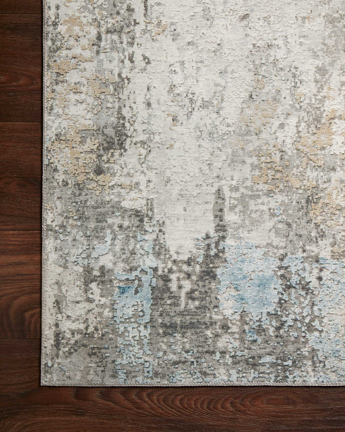 Antique abstract rug corner with gray, ivory, and light blue faded pattern on floor