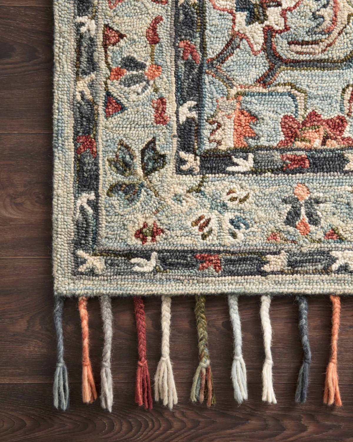 Close-up of sky blue hooked rug border with orange, green, and cream stitched pattern