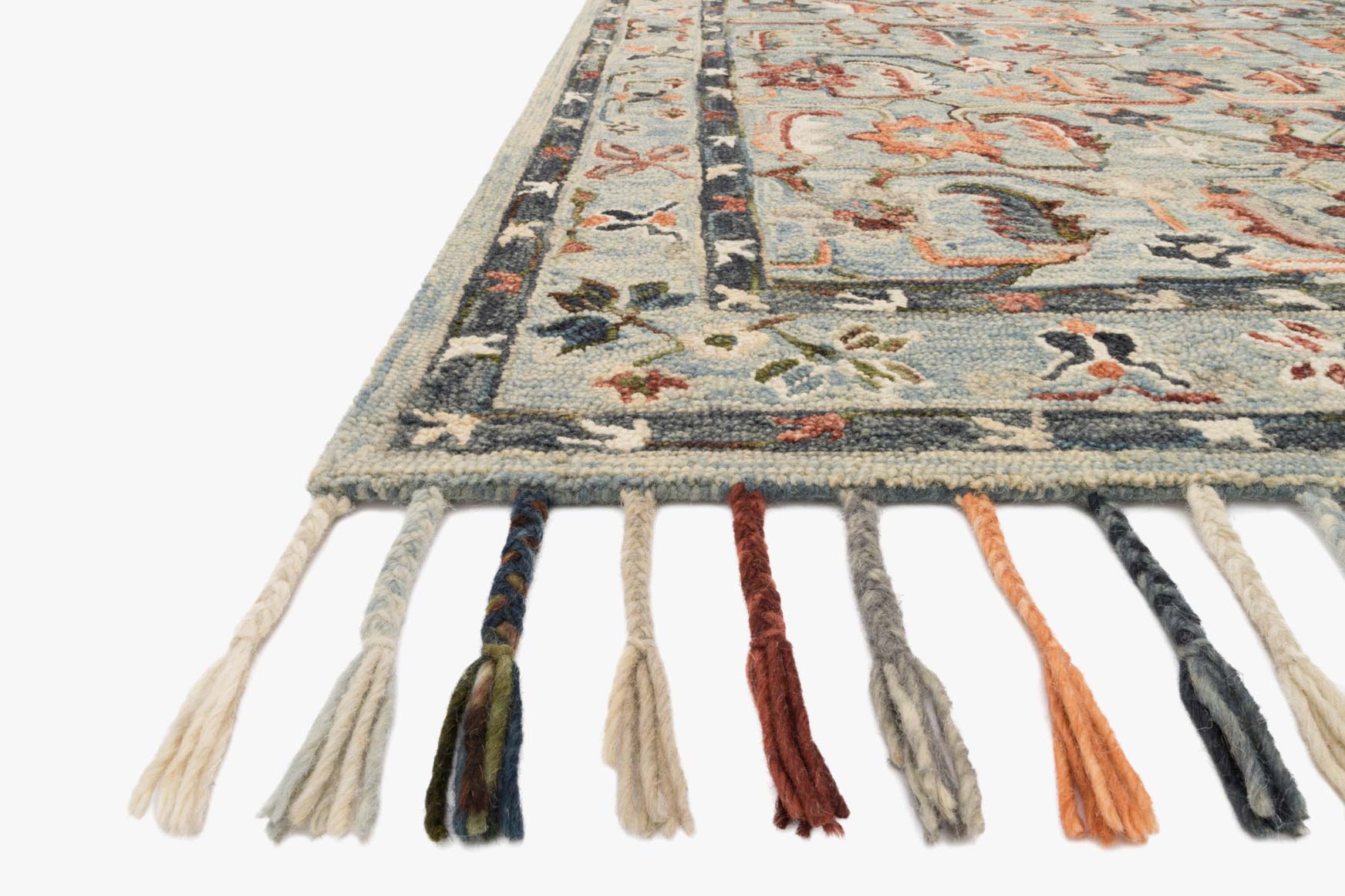 Sky blue rug corner with ornate border and multicolor tassel fringe