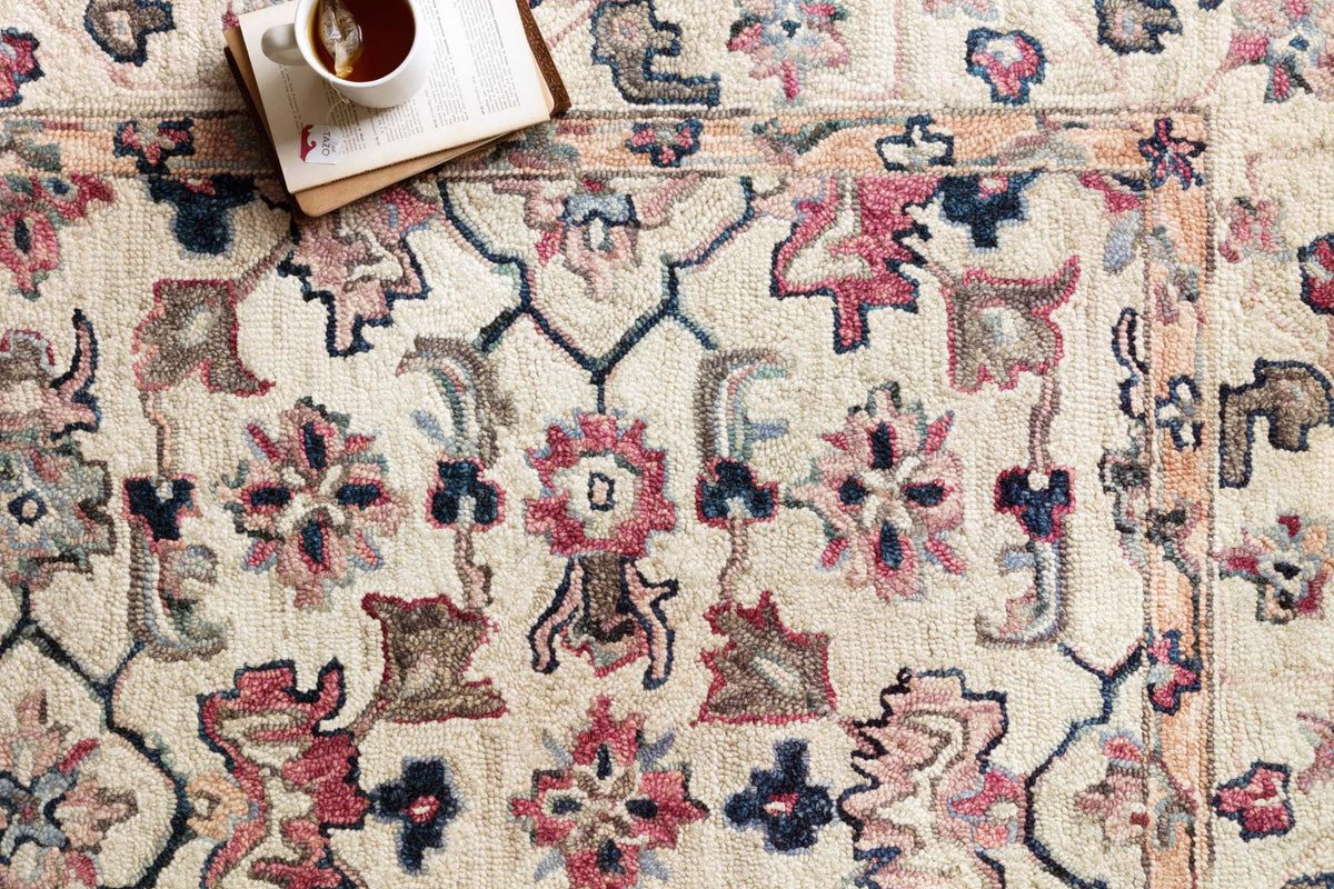 Close-up of ivory rug texture with navy, red, and blue floral and geometric hooked motifs