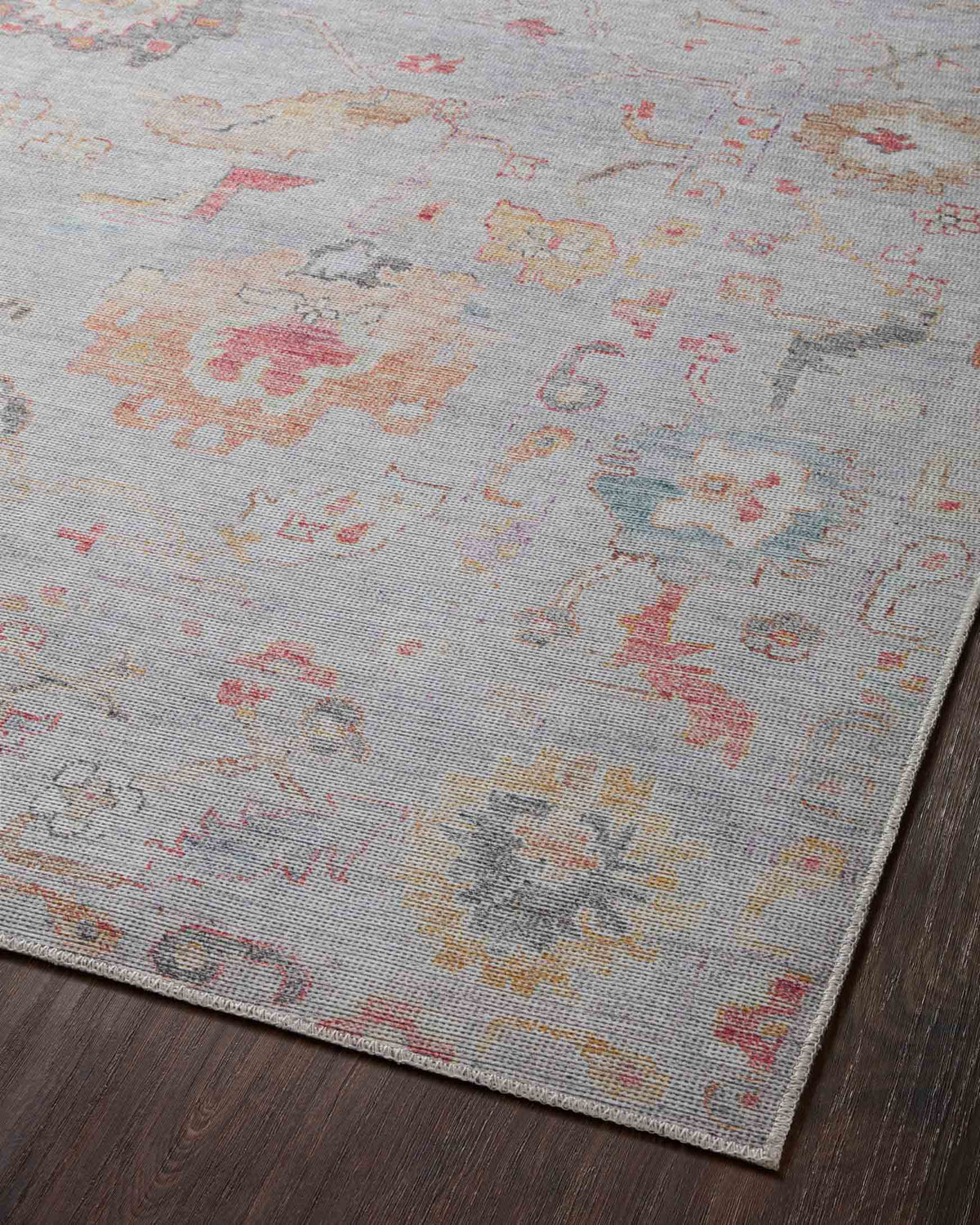 Top view of light silver rug with ornate faded medallions in coral, orange, and blue