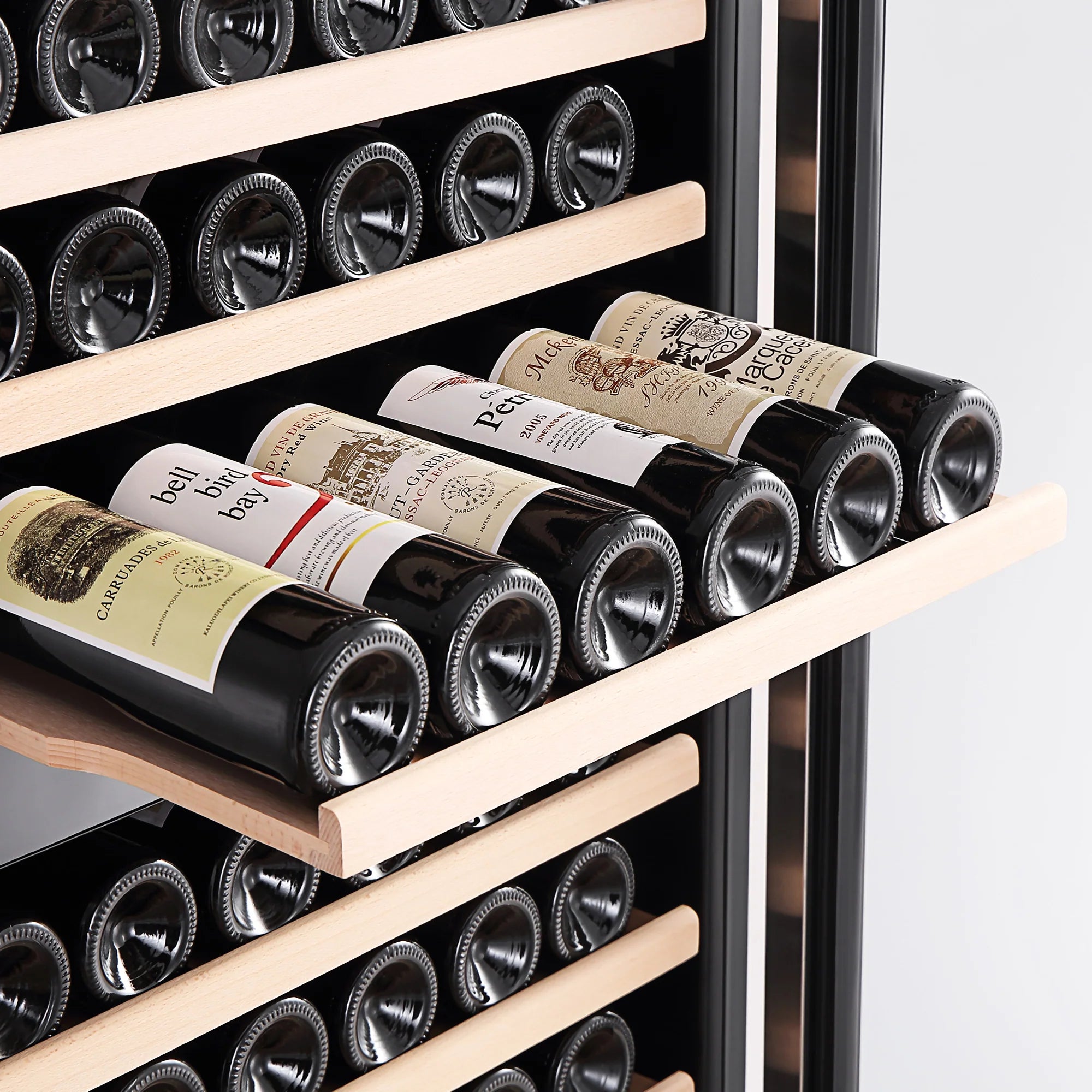 Wine bottles on light wood shelves inside a glass-front wine cooler