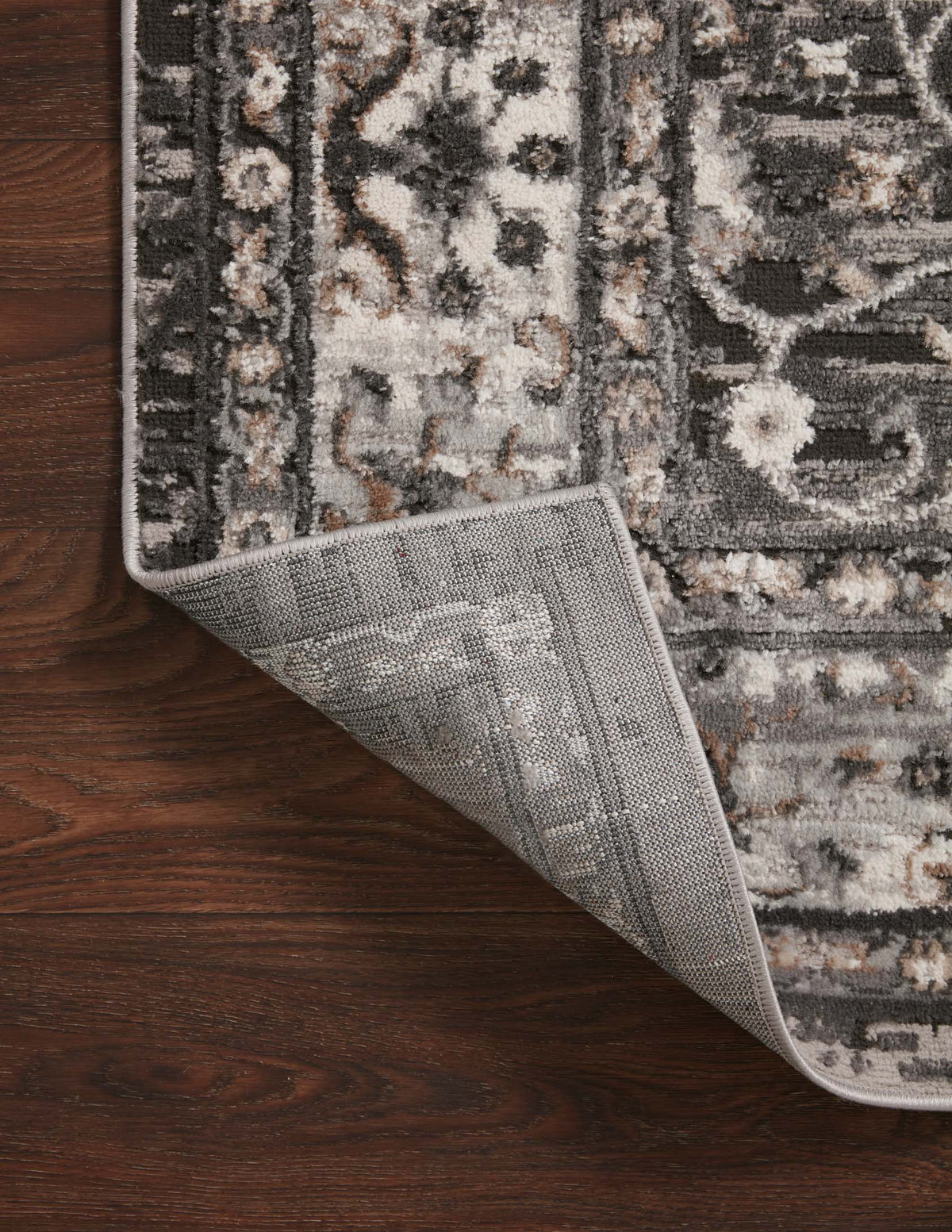 Charcoal and grey rug edge showing backing fabric and stitched trim