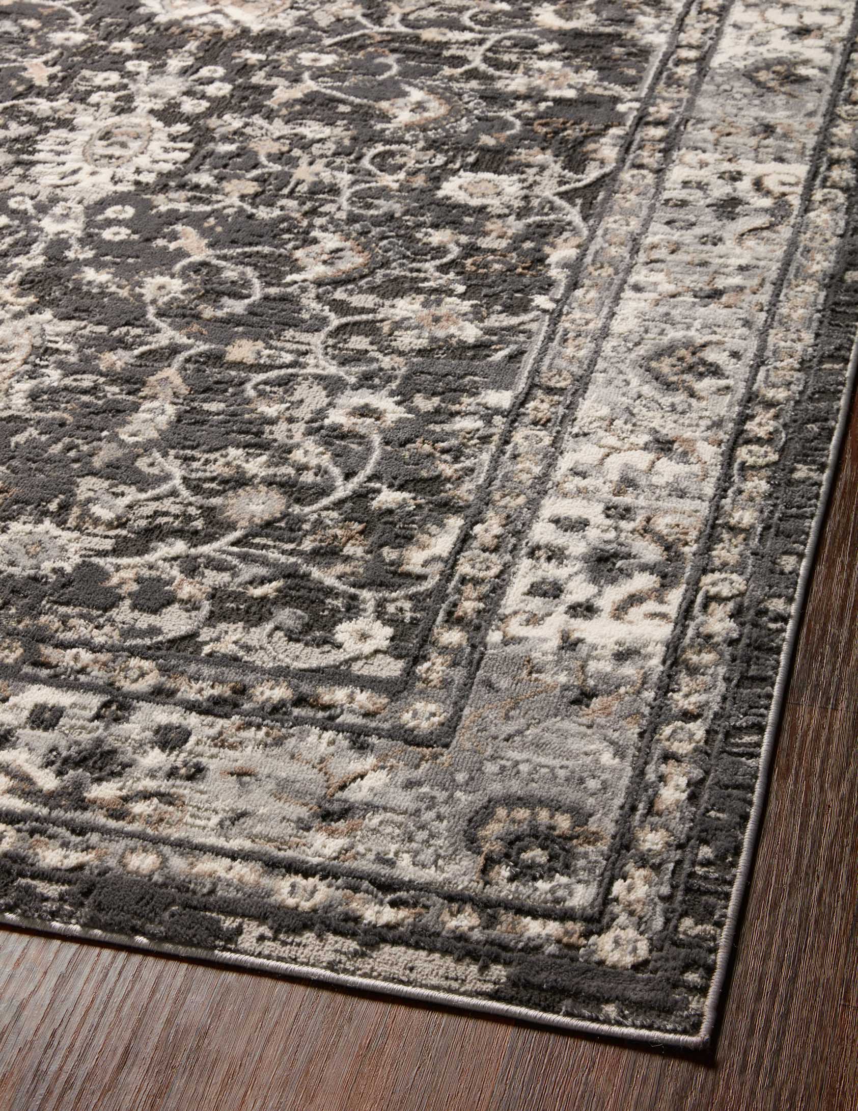 Charcoal and grey rug surface with scrolling vines, floral clusters, and border