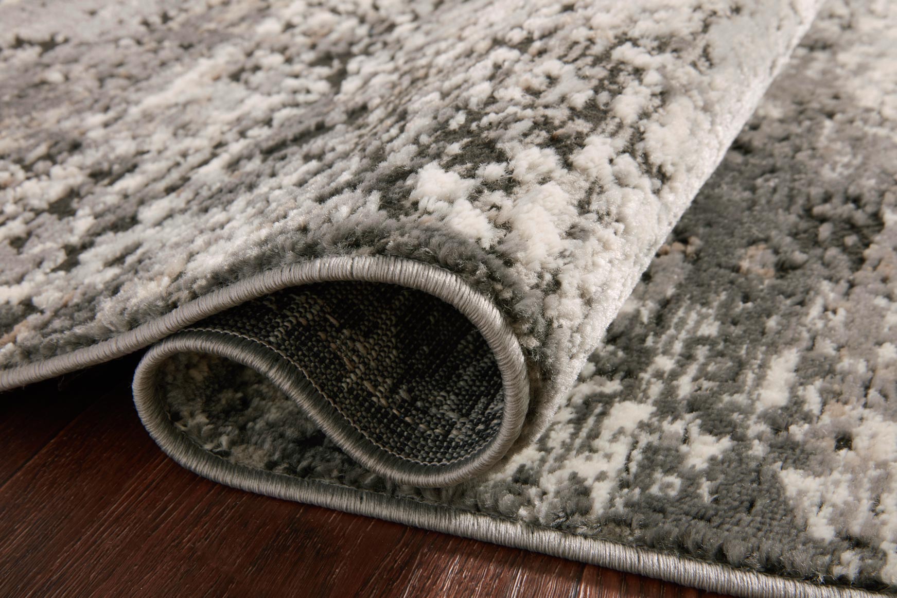 Charcoal and granite power-loomed rug with distressed texture and short gray border edge roll.