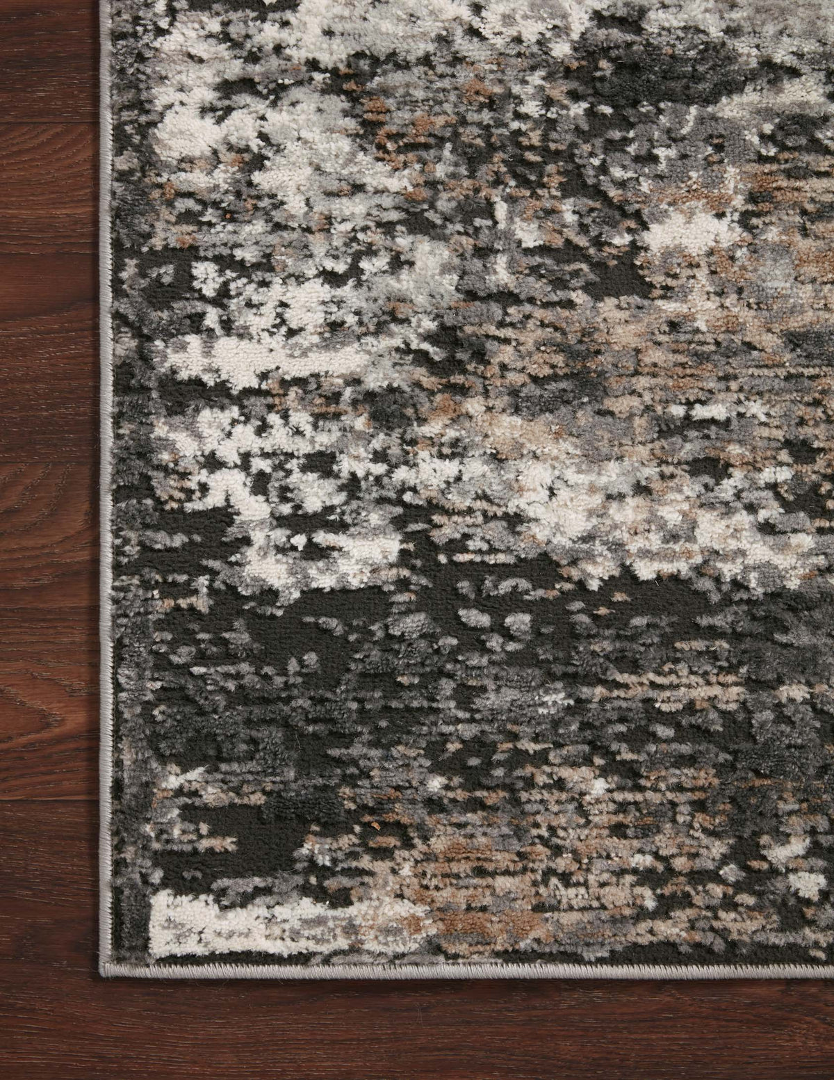 Charcoal, granite, and speckled rug with distressed pattern and finished border on dark flooring.