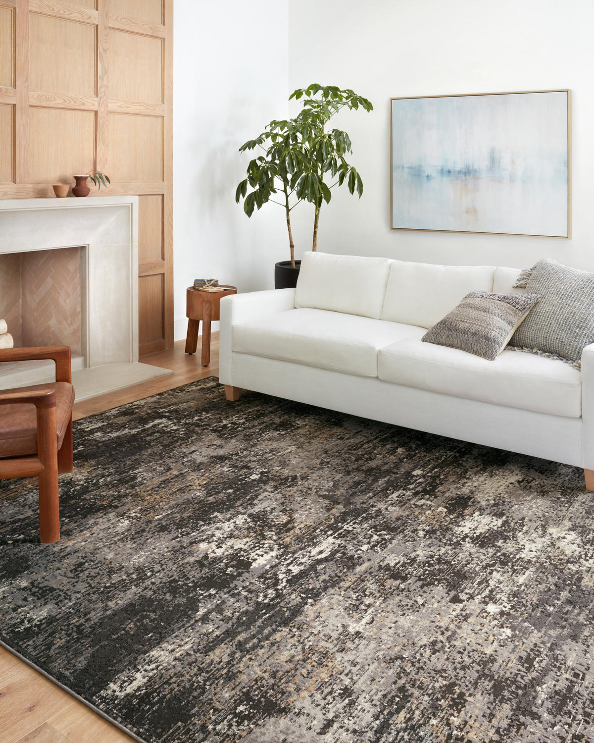 Charcoal and granite distressed rug with short pile, placed under living room sofa.