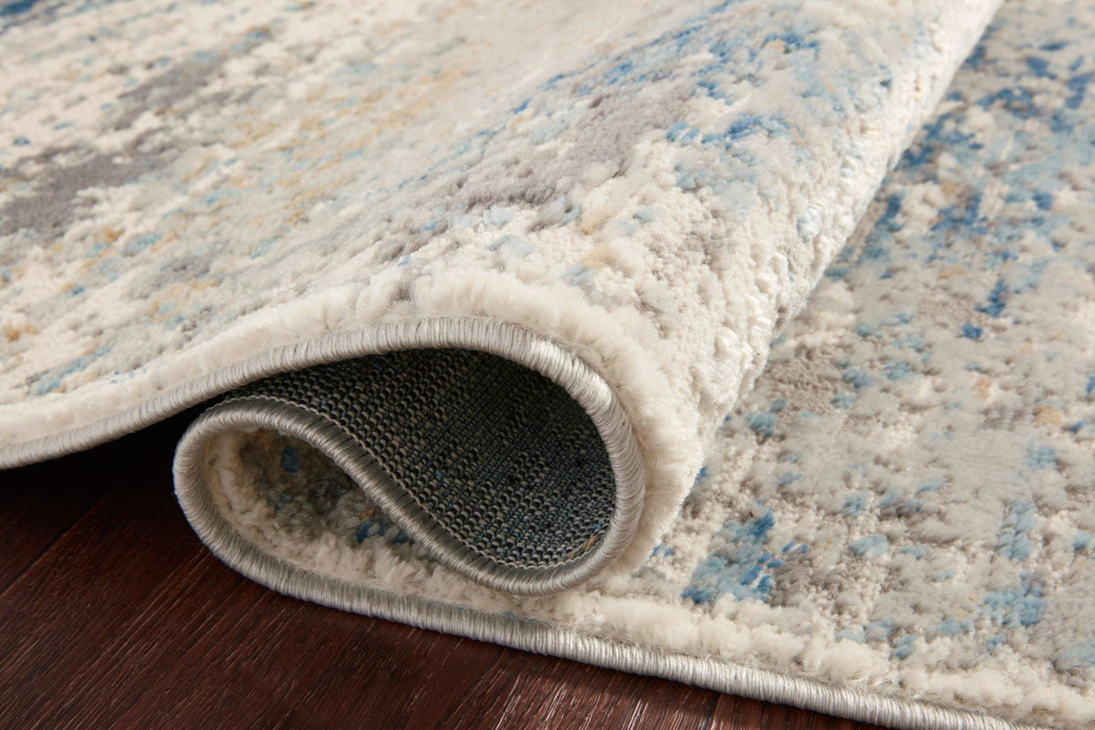 Ivory and ocean rug edge close-up with textured pile and stitched border.