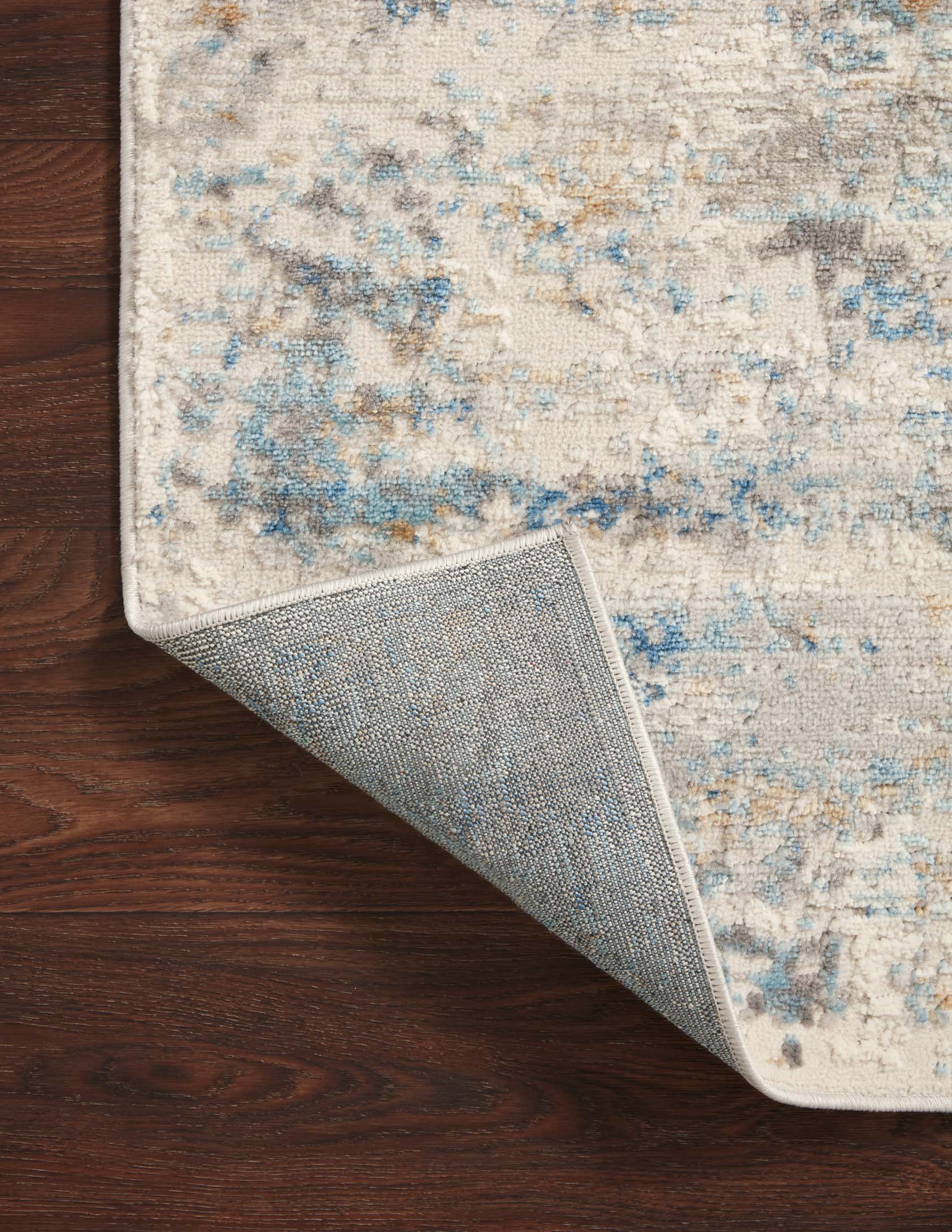 Ivory and ocean rug corner lifted slightly, showing underside and flat textured back.