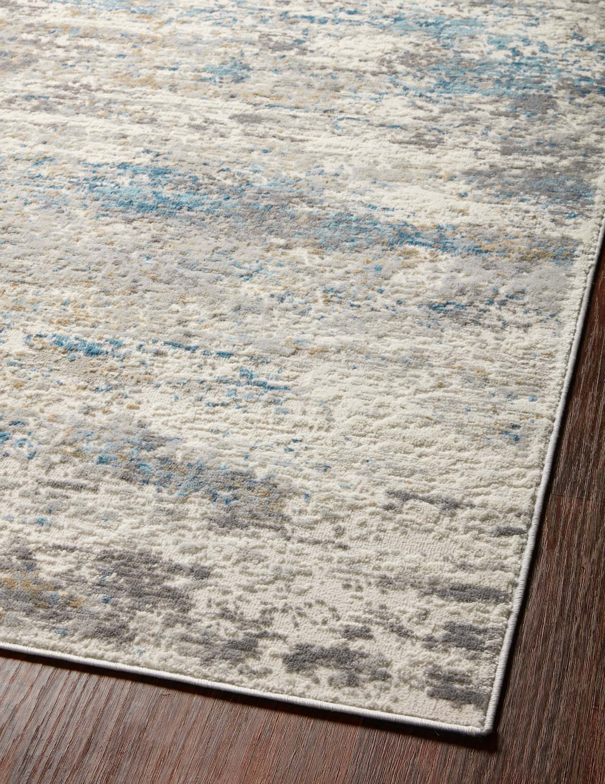 Ivory and ocean area rug close-up with abstract distressed pattern and clean border.