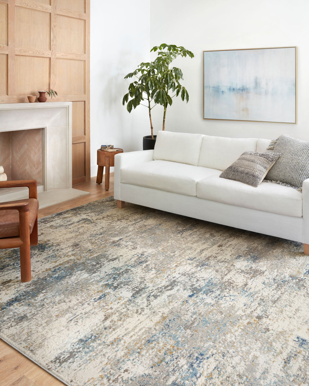 Ivory and ocean area rug under living room sofa, featuring an abstract distressed pattern.