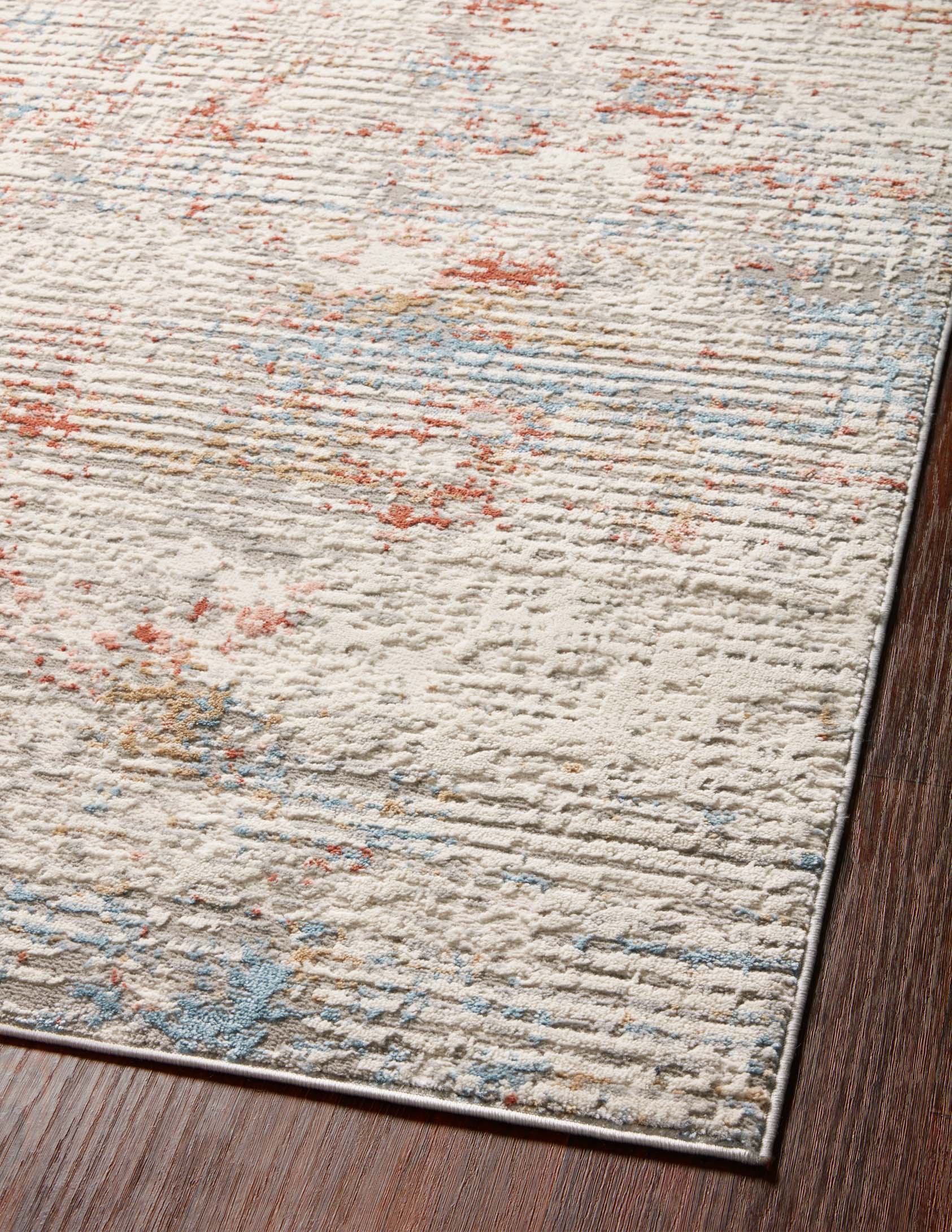 Close-up of ivory rug texture with distressed red and light blue speckled pattern