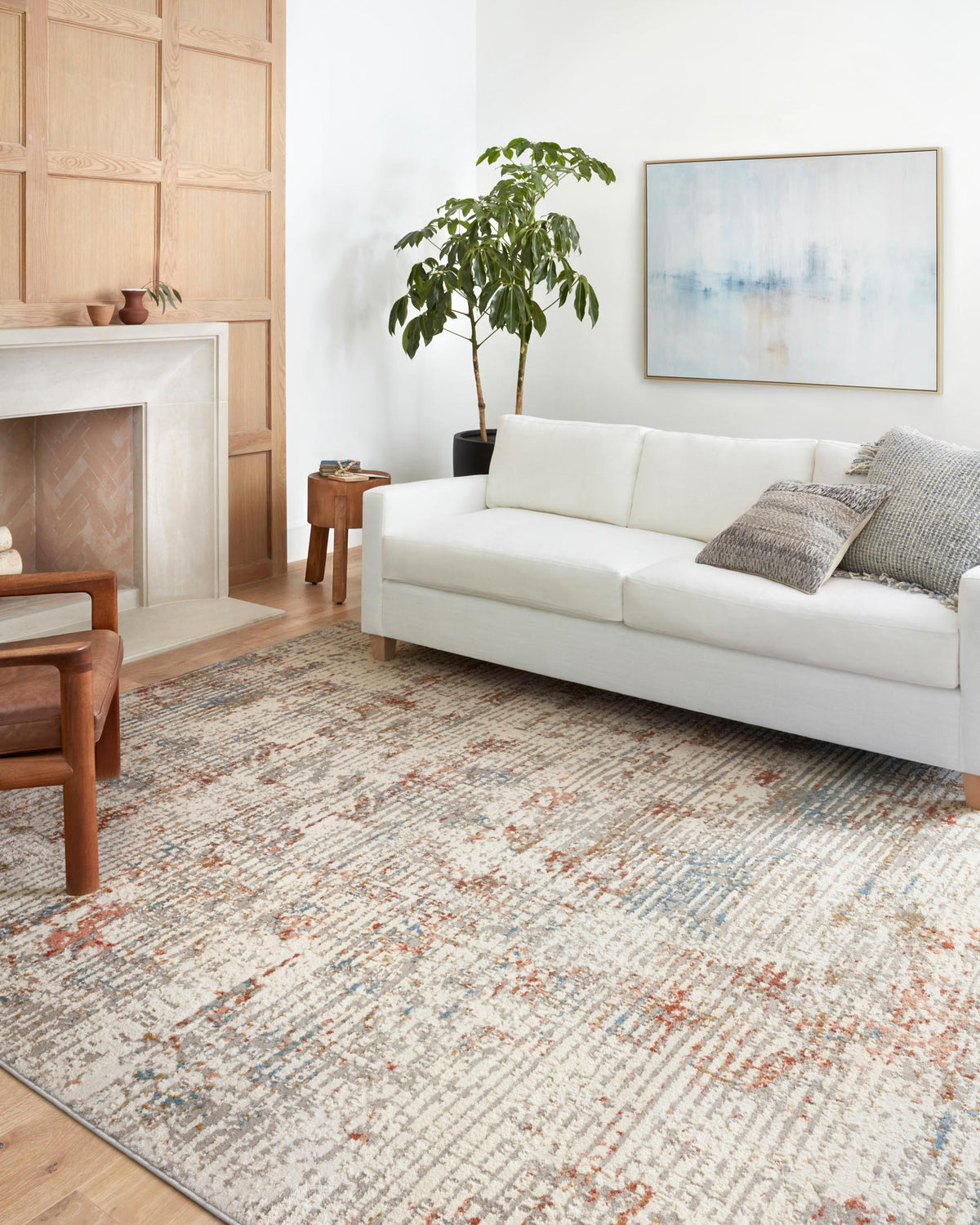 Ivory rug with distressed red and light blue abstract pattern, shown on a living room floor