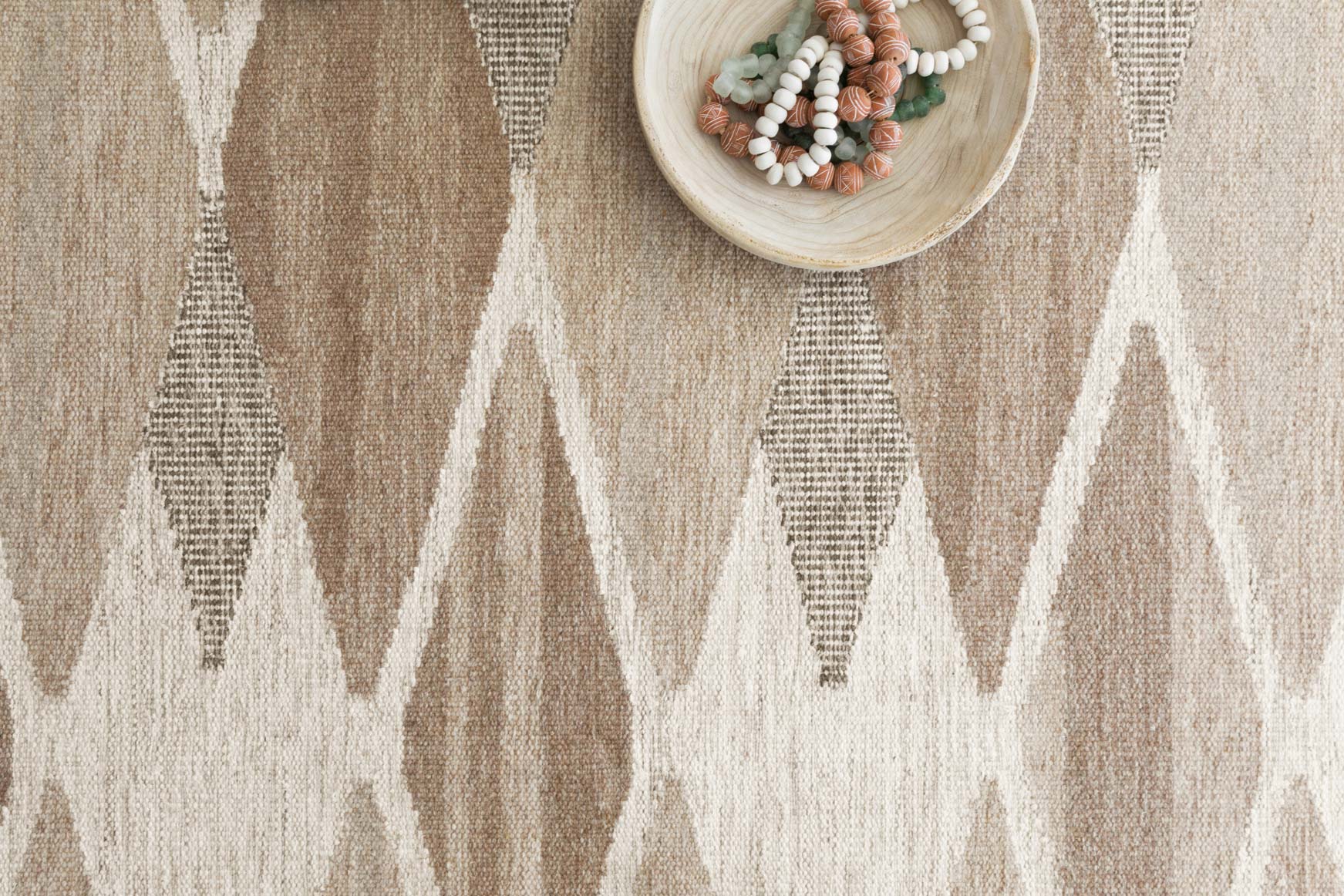Close-up of taupe and cream hand-woven rug texture with geometric motif