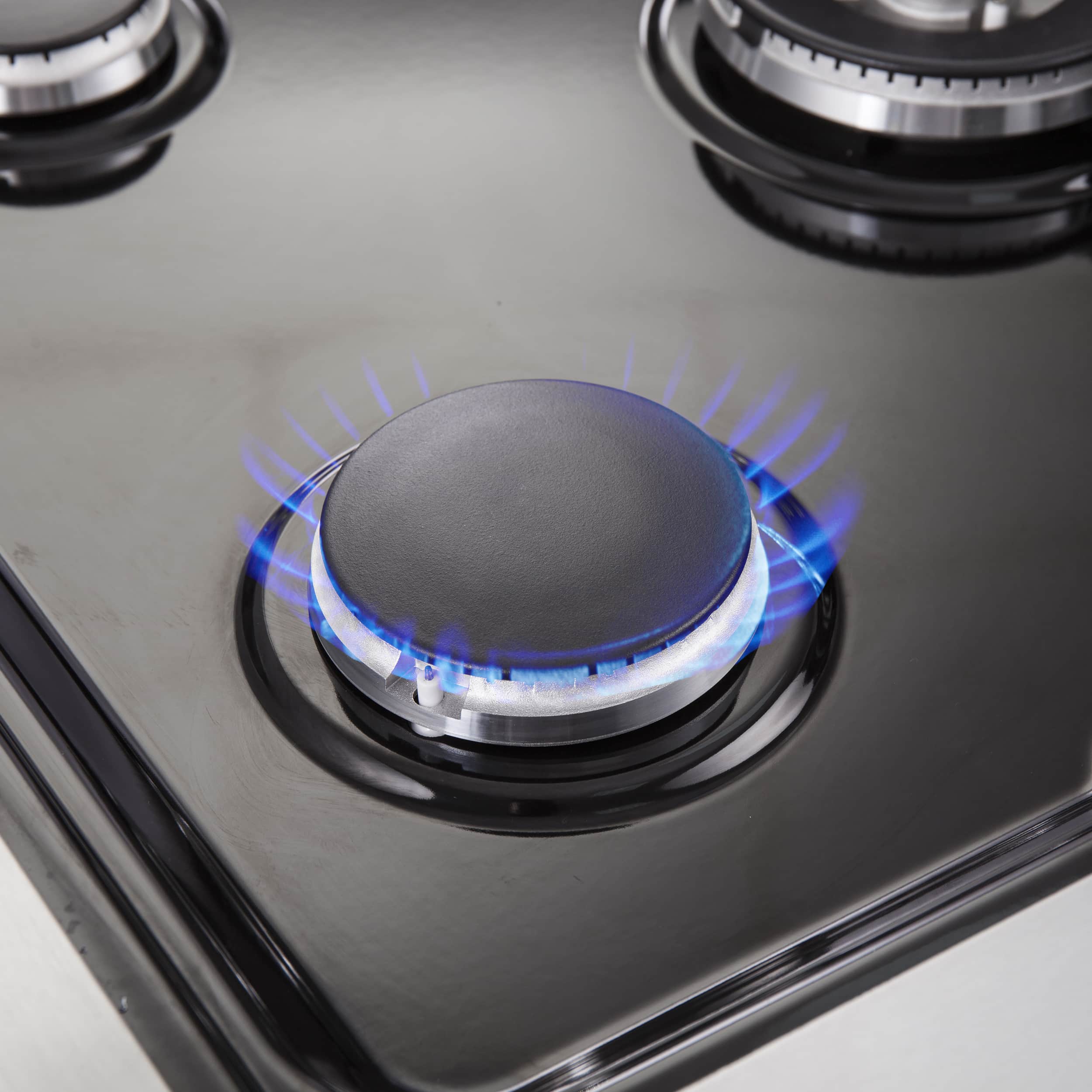Dual fuel range cooktop burner with blue flame on stainless surface