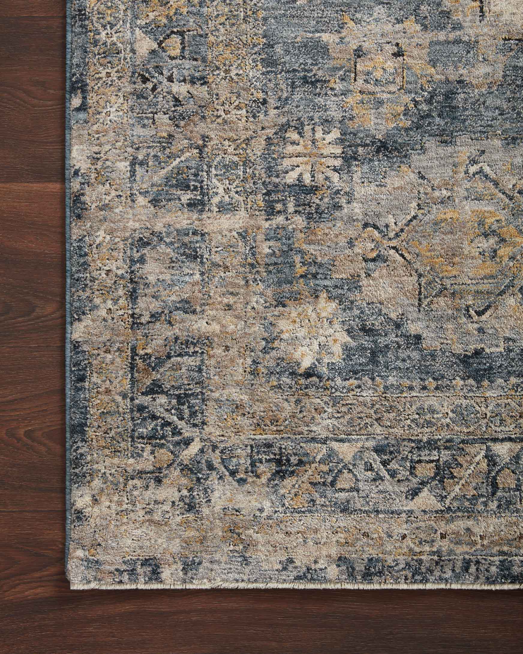 Close-up transitional rug edge with distressed blue and taupe medallion pattern.