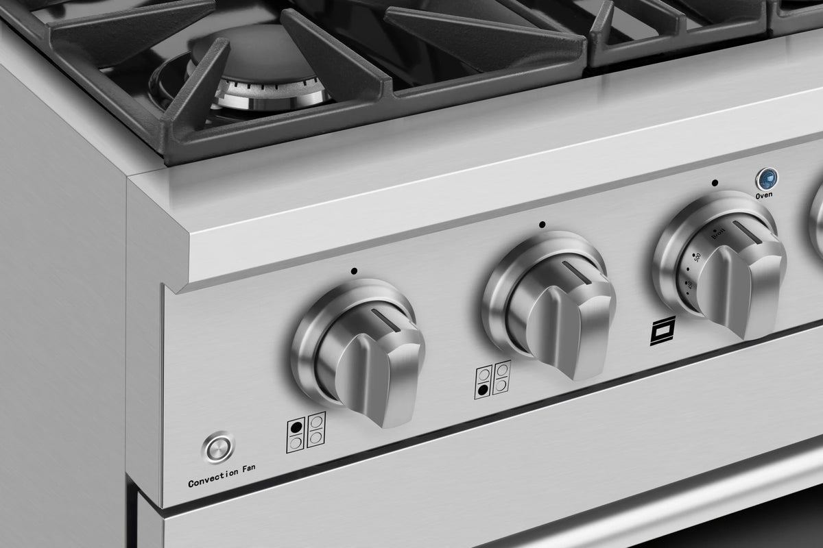 Gas range control panel with four metal knobs and burner grate corner