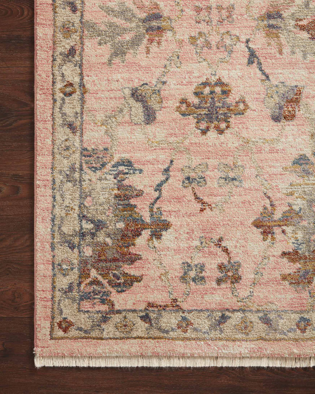 Blush floral rug corner close-up with decorative border and short fringe