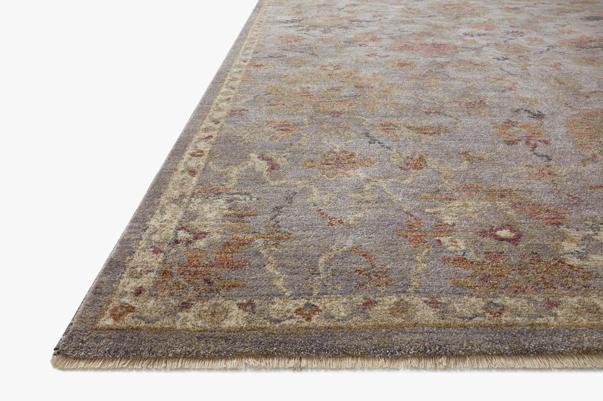Close-up of silver-gray distressed floral rug edge with stitched border and short fringe