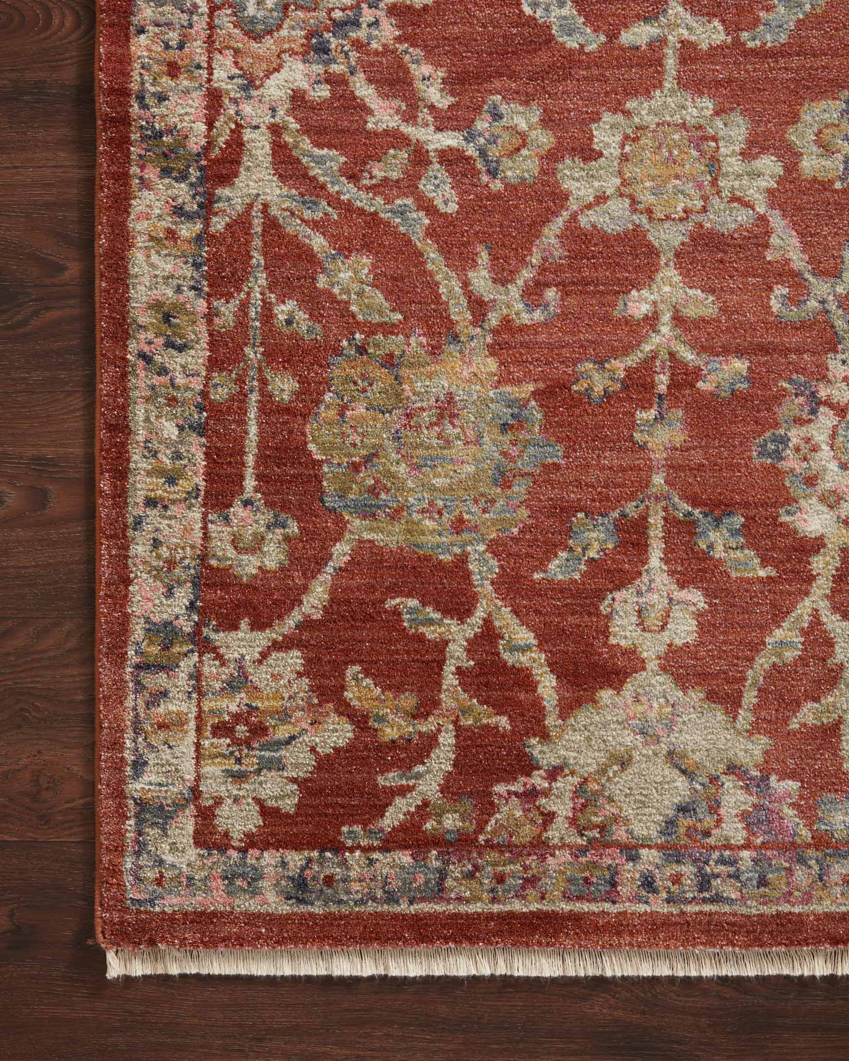 Red rug close-up with ornate medallion motifs and short fringe along the border