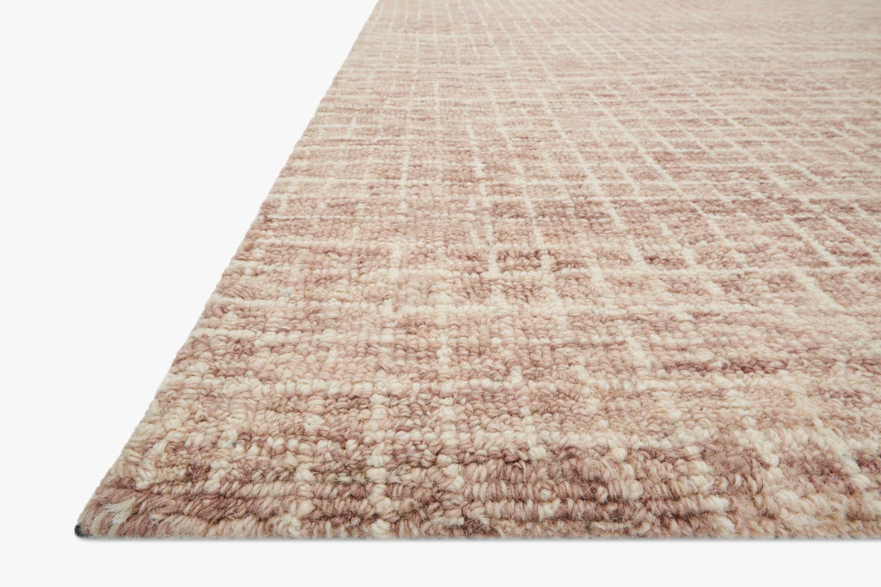 Corner view of blush hooked rug with looped pile and subtle grid texture