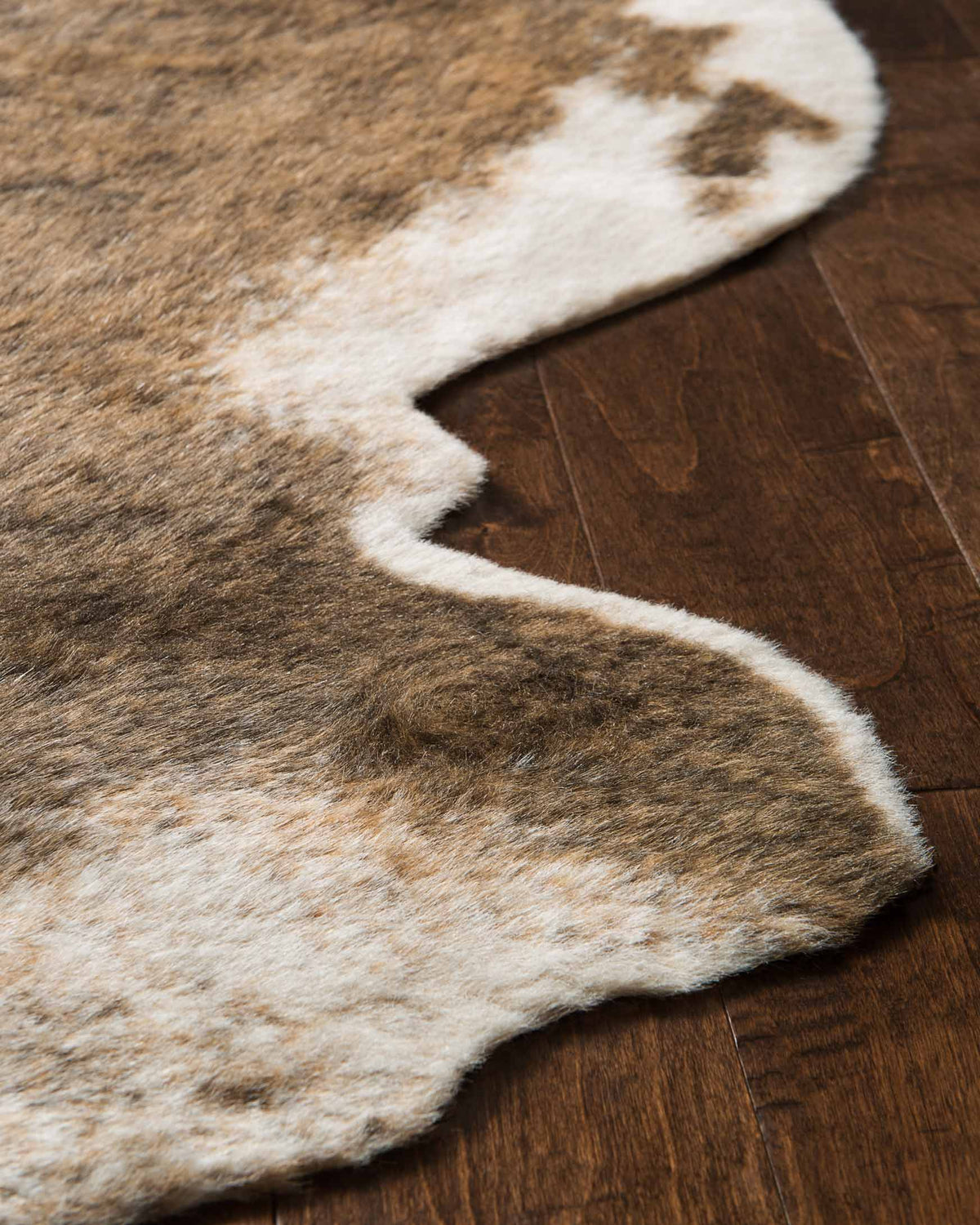 Close-up of camel-brown and cream cowhide pattern rug with irregular patches
