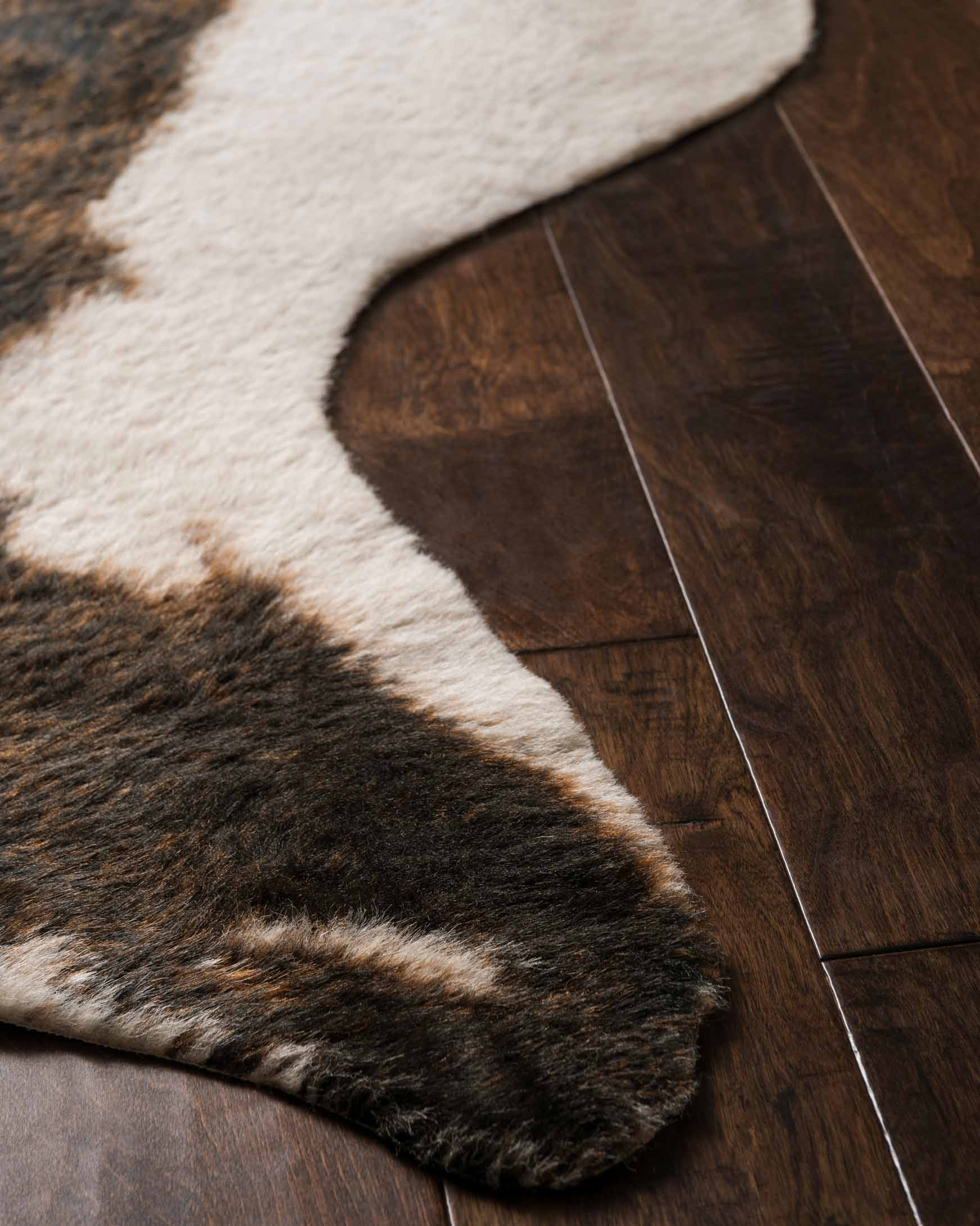 Corner of beige and brown cowhide-style rug with dark mottled border