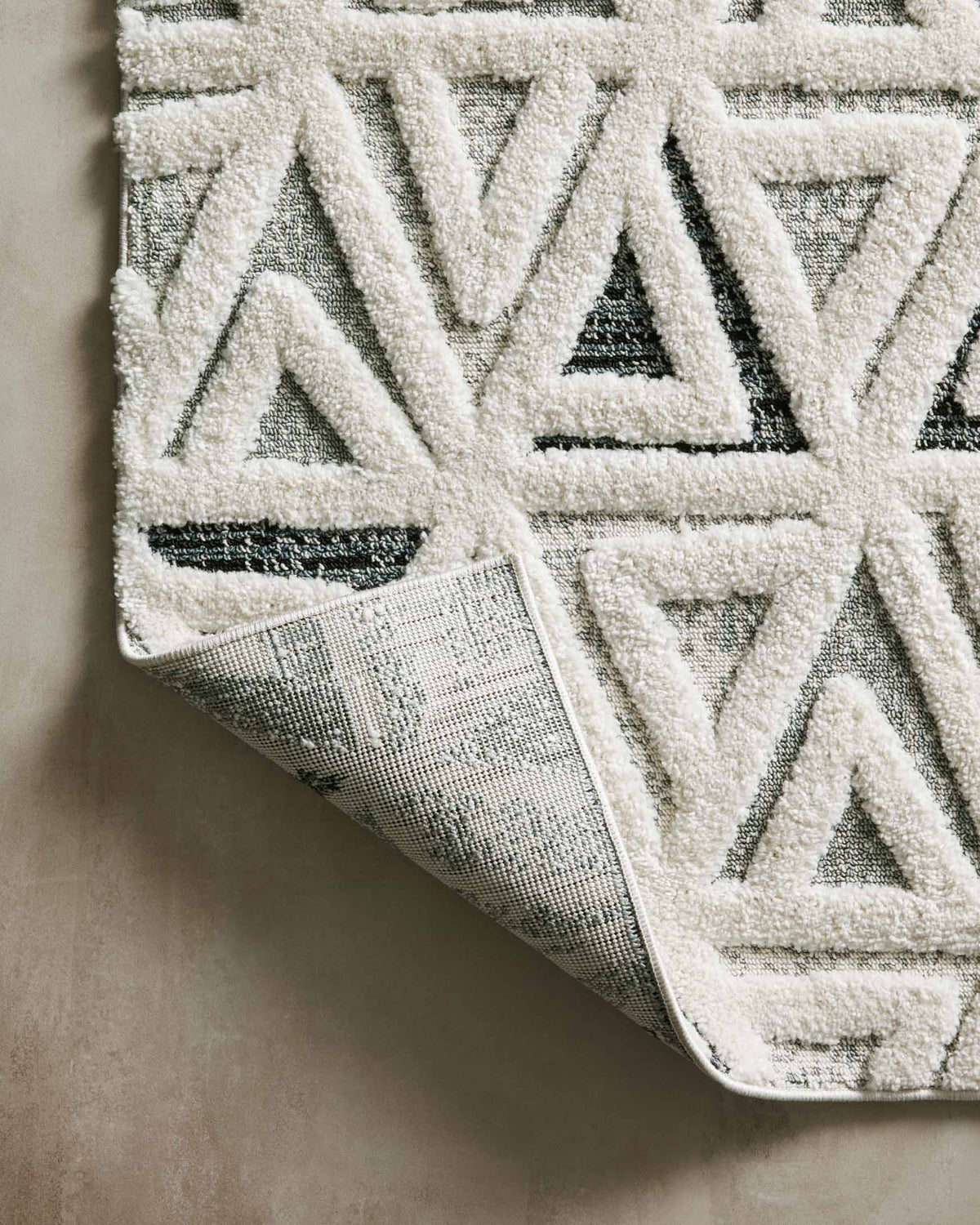 Cream and navy geometric rug with textured pile; corner shows woven backing underside