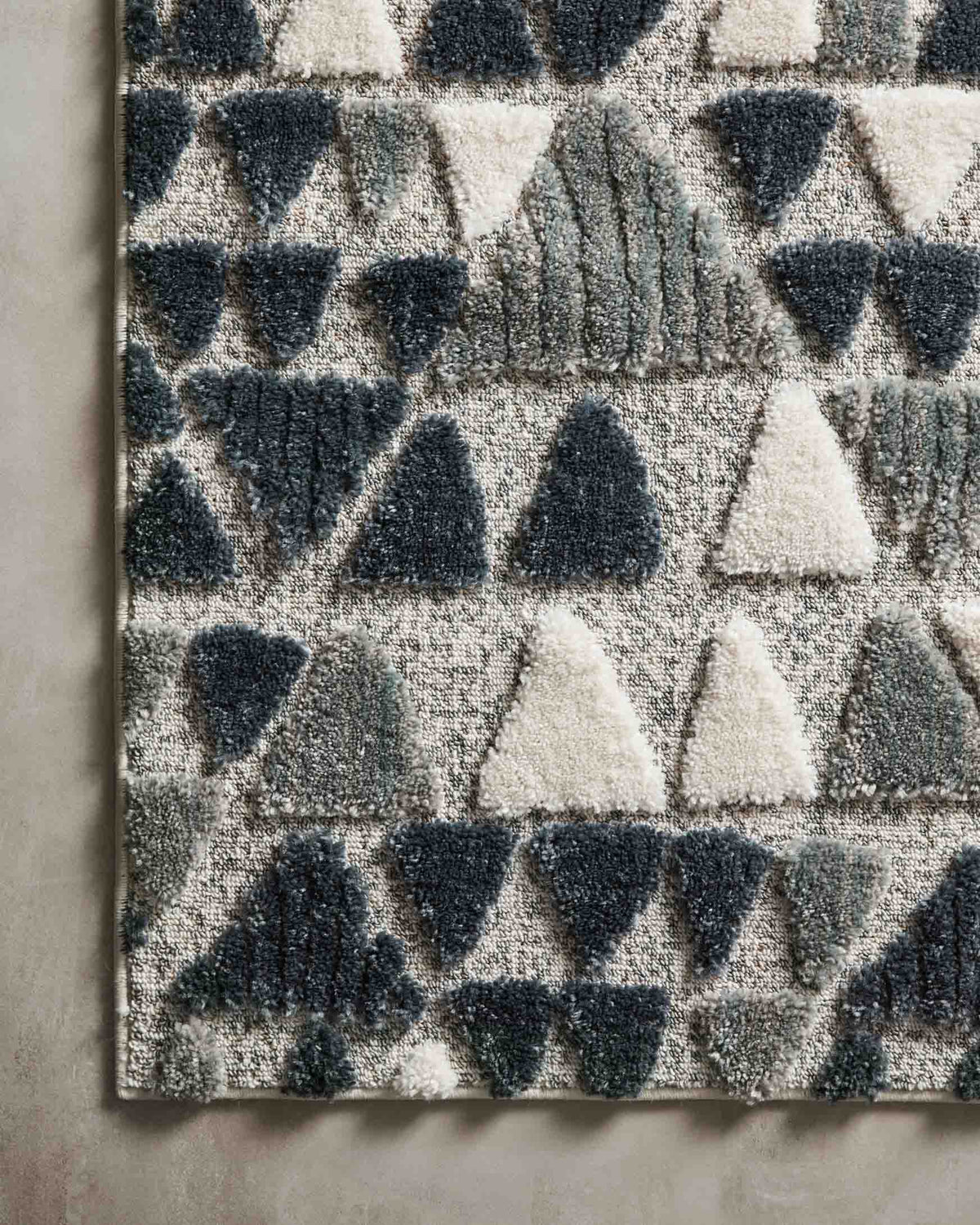Edge view of slate and denim rug showing short pile and triangle motif
