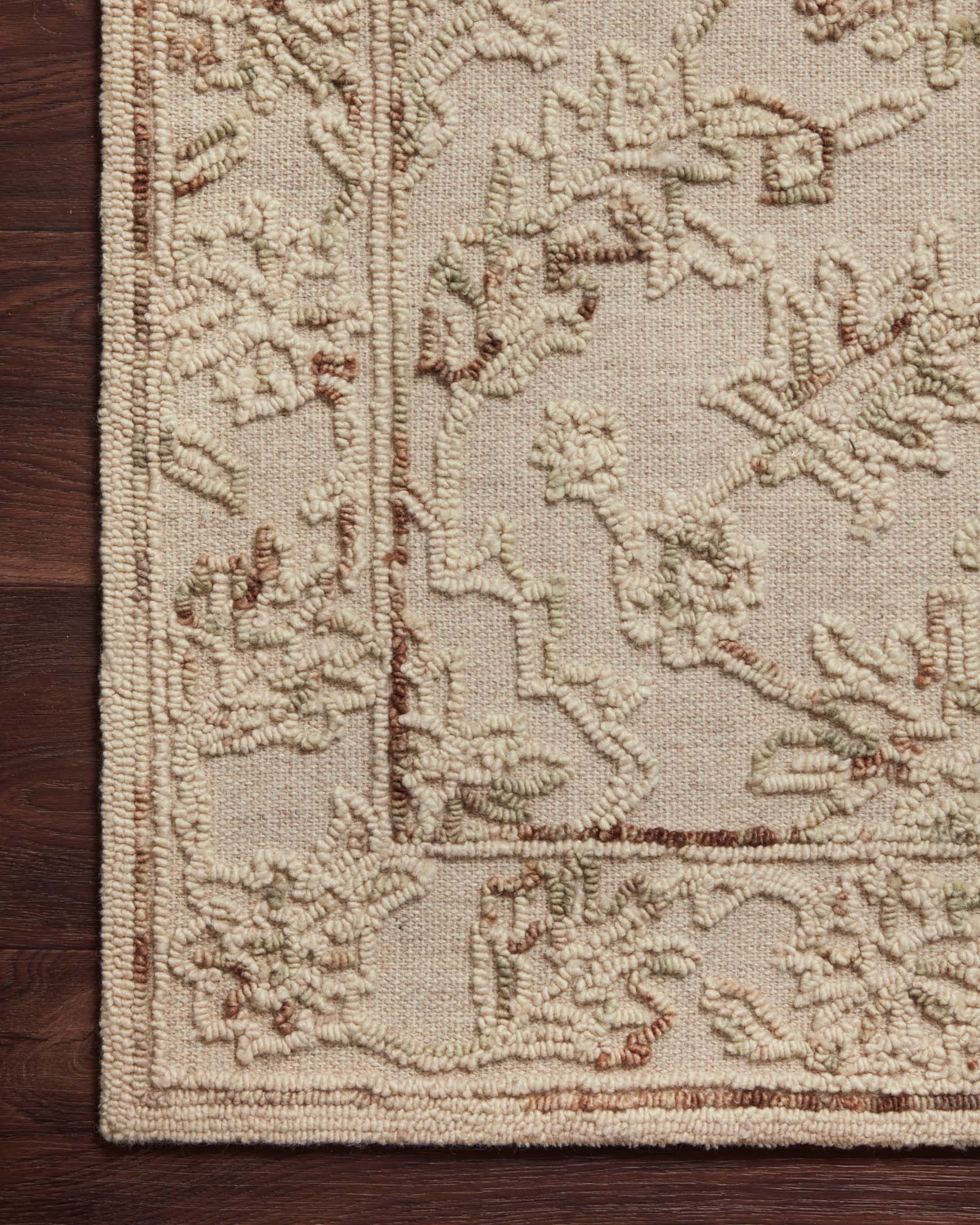 Traditional hooked rug close-up of border and dense motifs in natural beige with sage tones.