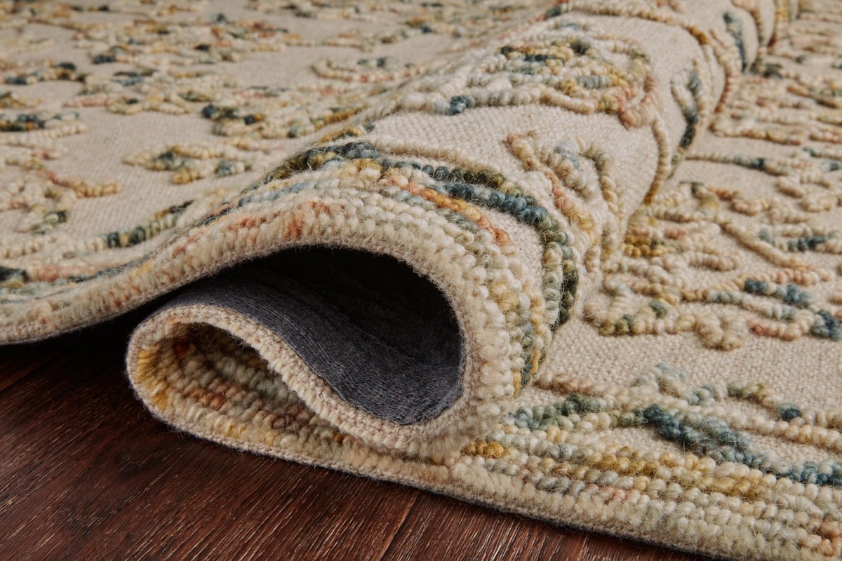 Hooked rug showing low pile texture and looped border trim on beige with blue-green accents
