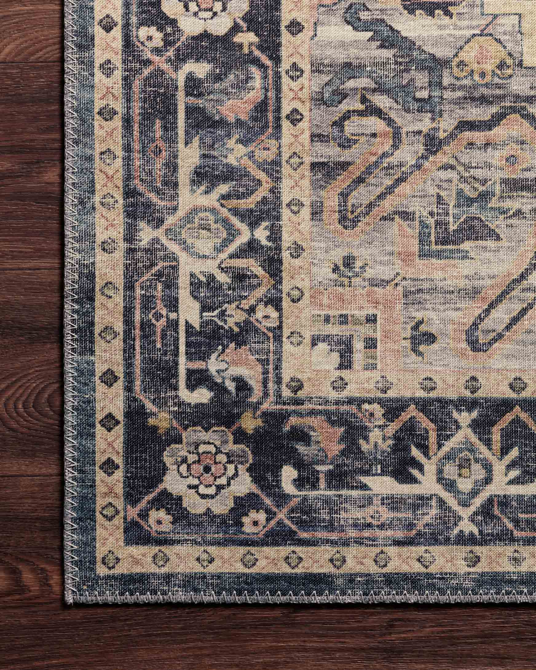 Corner detail of navy and light blue traditional rug on dark wood floor