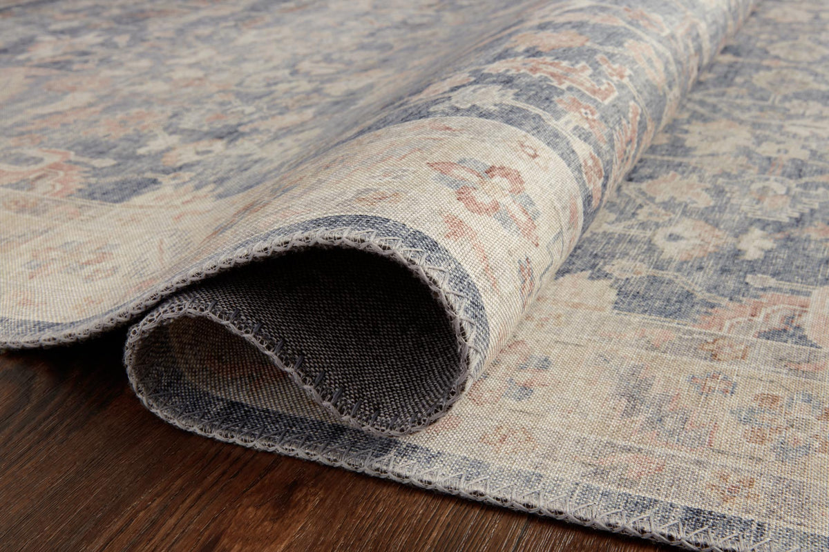 Traditional power-loomed rug rolled edge showing blue and cream surface with gray backing