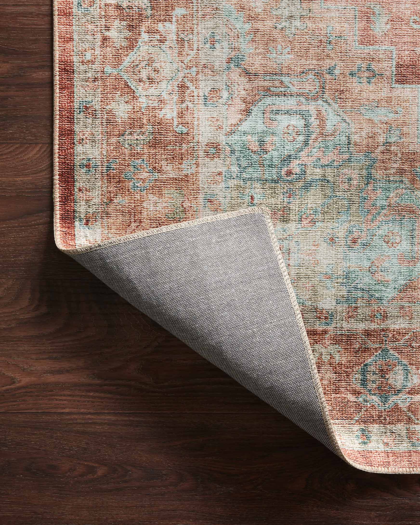 Corner view showing underside of terracotta and aqua rug with gray backing