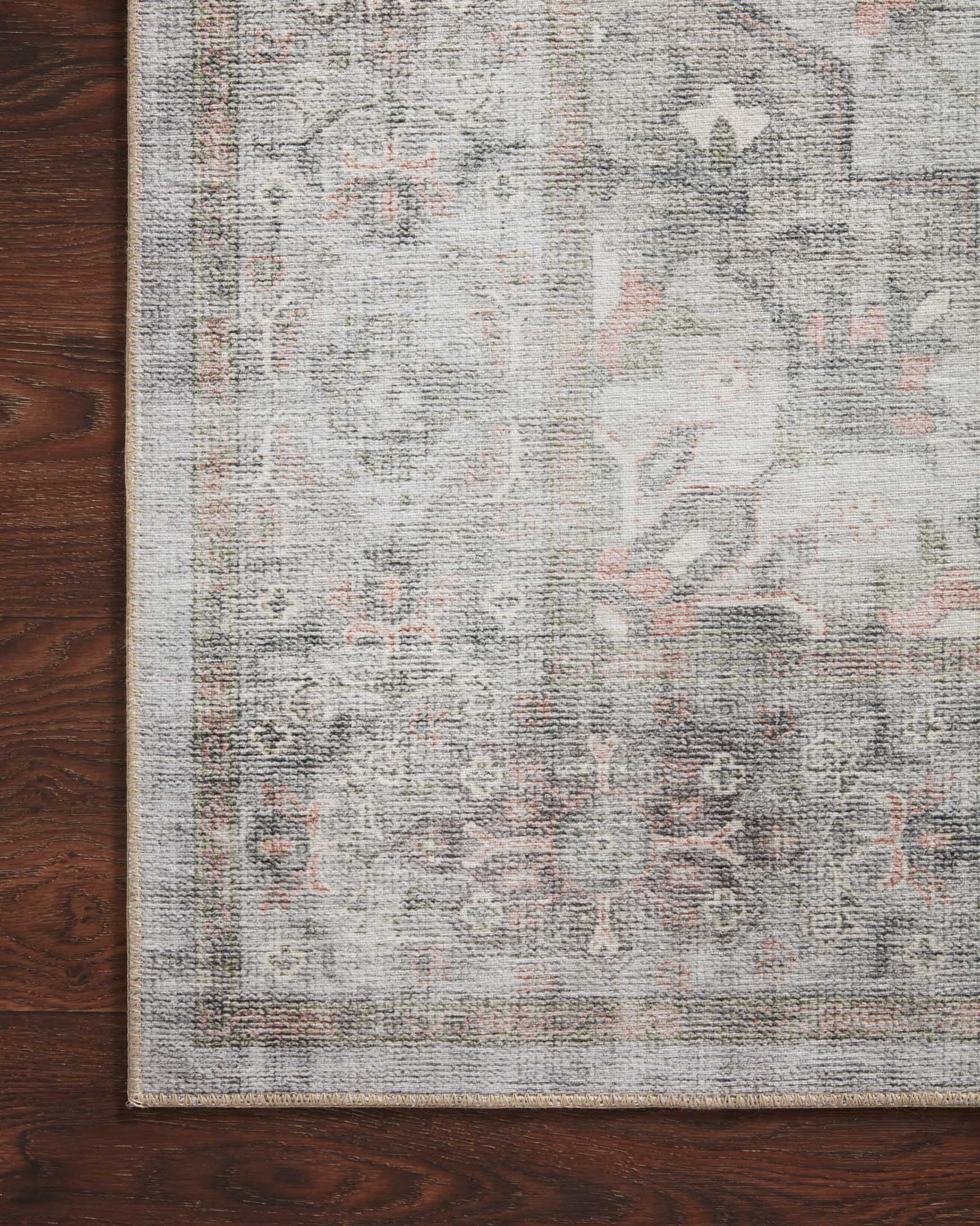 Close-up of rug surface with light gray field and small blush-orange motif details.