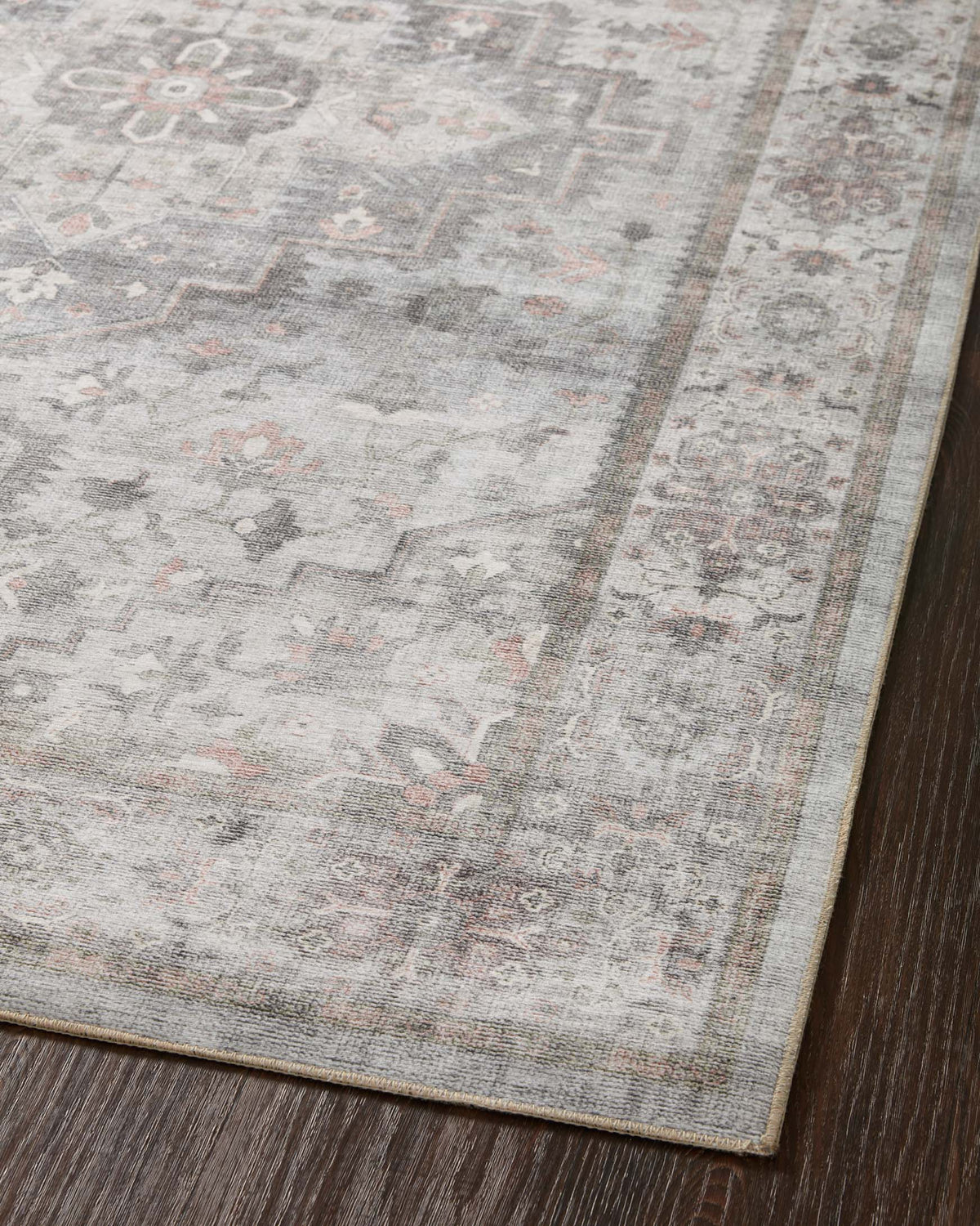 Edge close-up of traditional rug with distressed light gray pattern and border stripe.