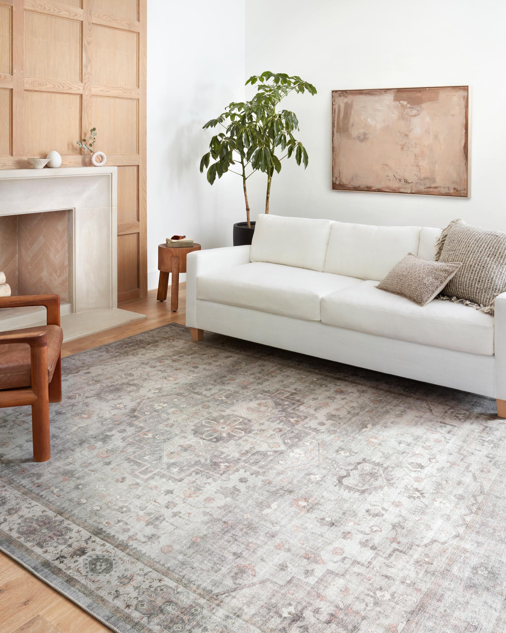 Traditional area rug covering the floor, light gray with muted blush detail and motif.