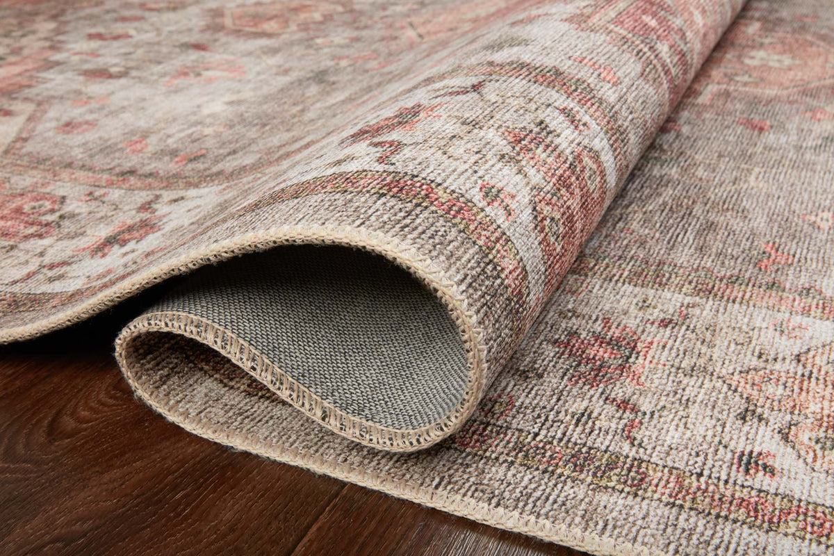 Rolled edge of traditional rug showing light gray pile and textured woven border