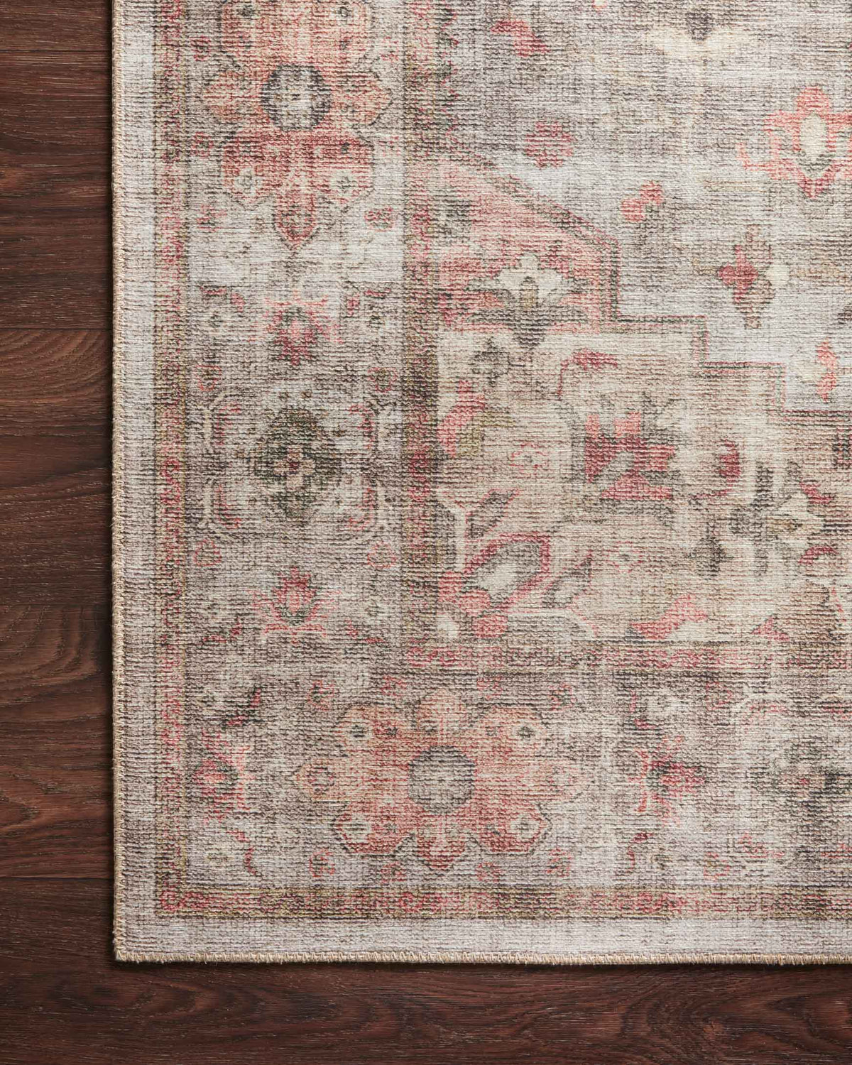 Traditional rug corner close-up with light gray background and rust coral geometric motifs
