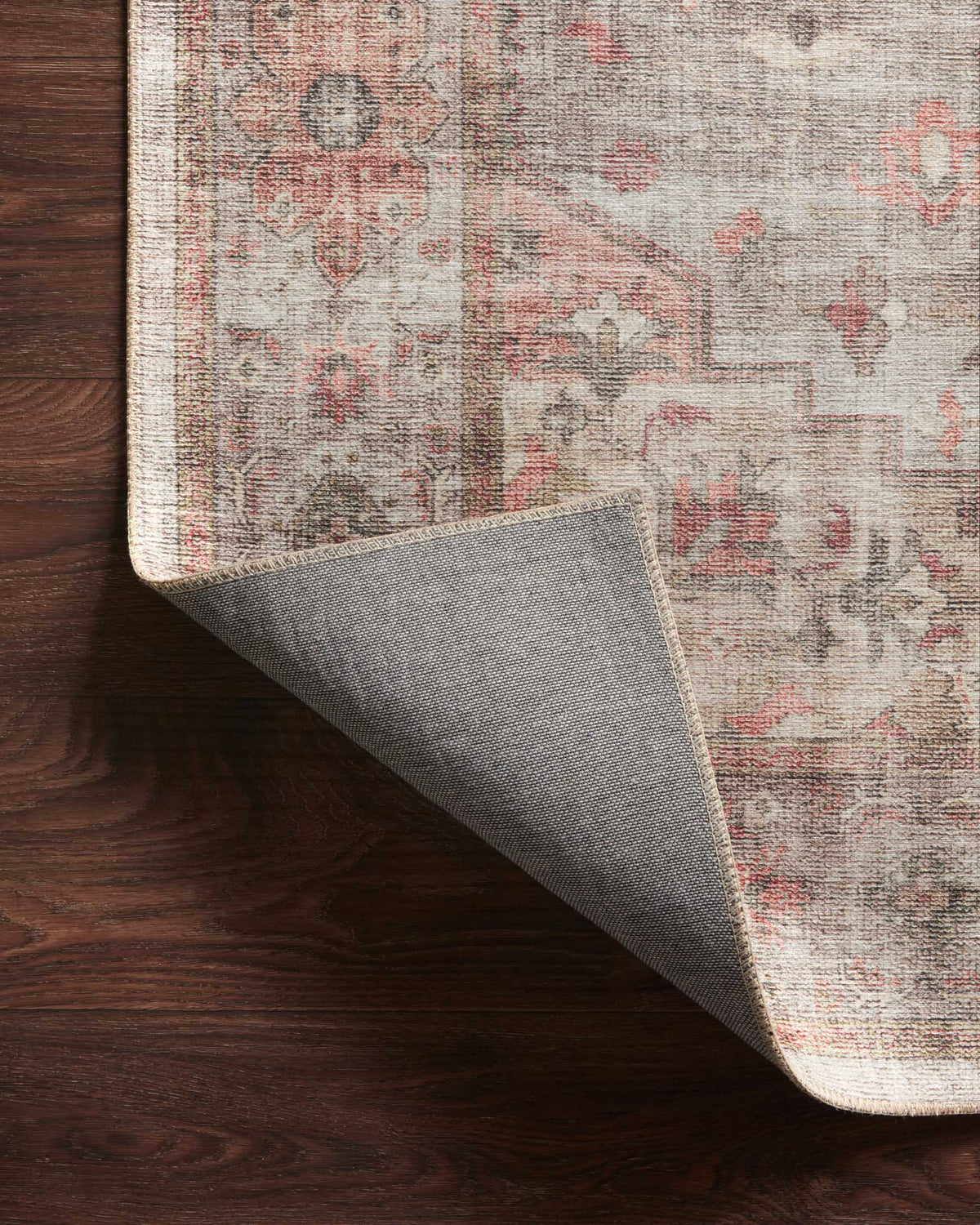 Traditional rug corner with gray reverse backing visible and rust coral patterned surface