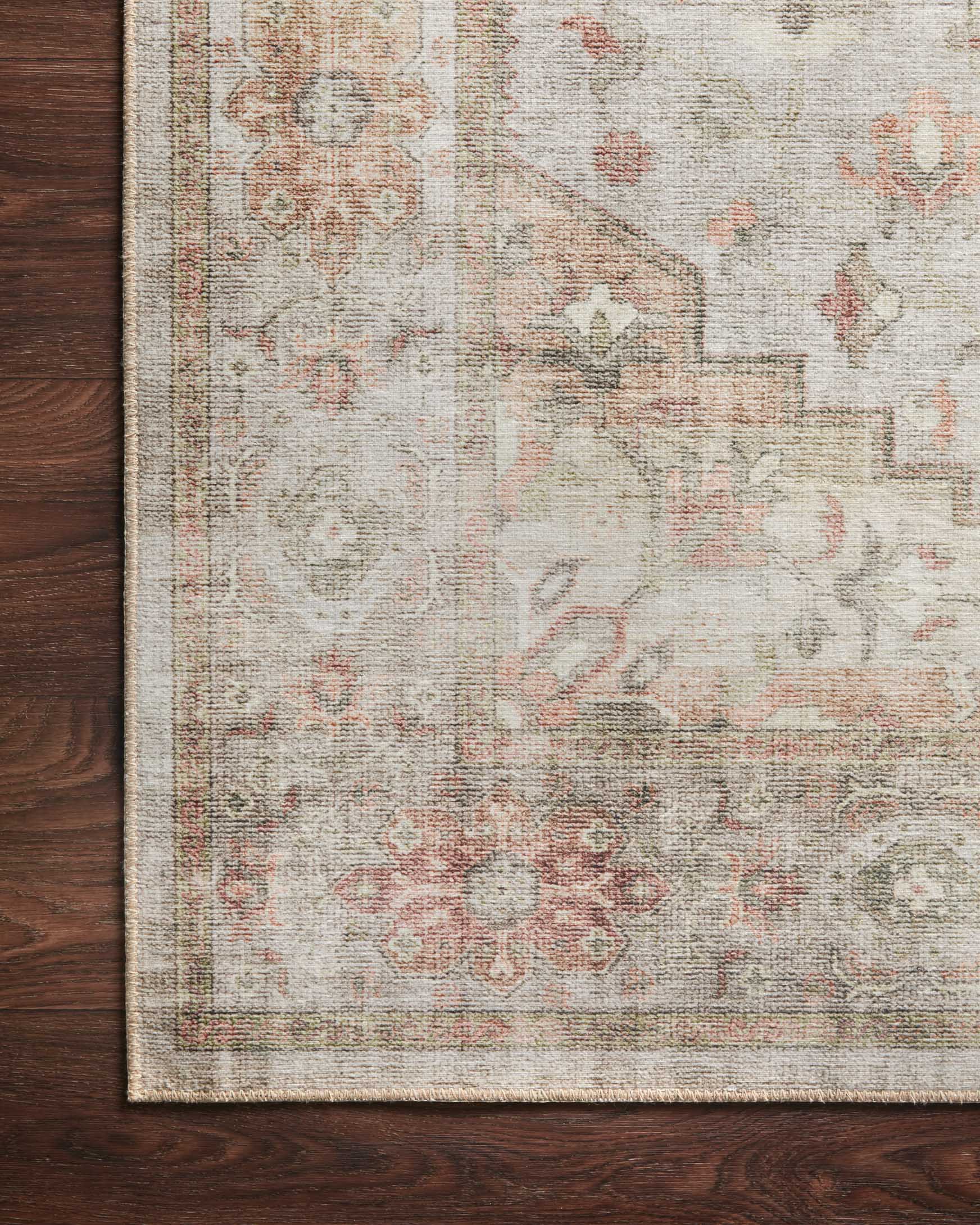 Traditional power-loomed rug edge detail with distressed pattern in sage, beige, and muted rust