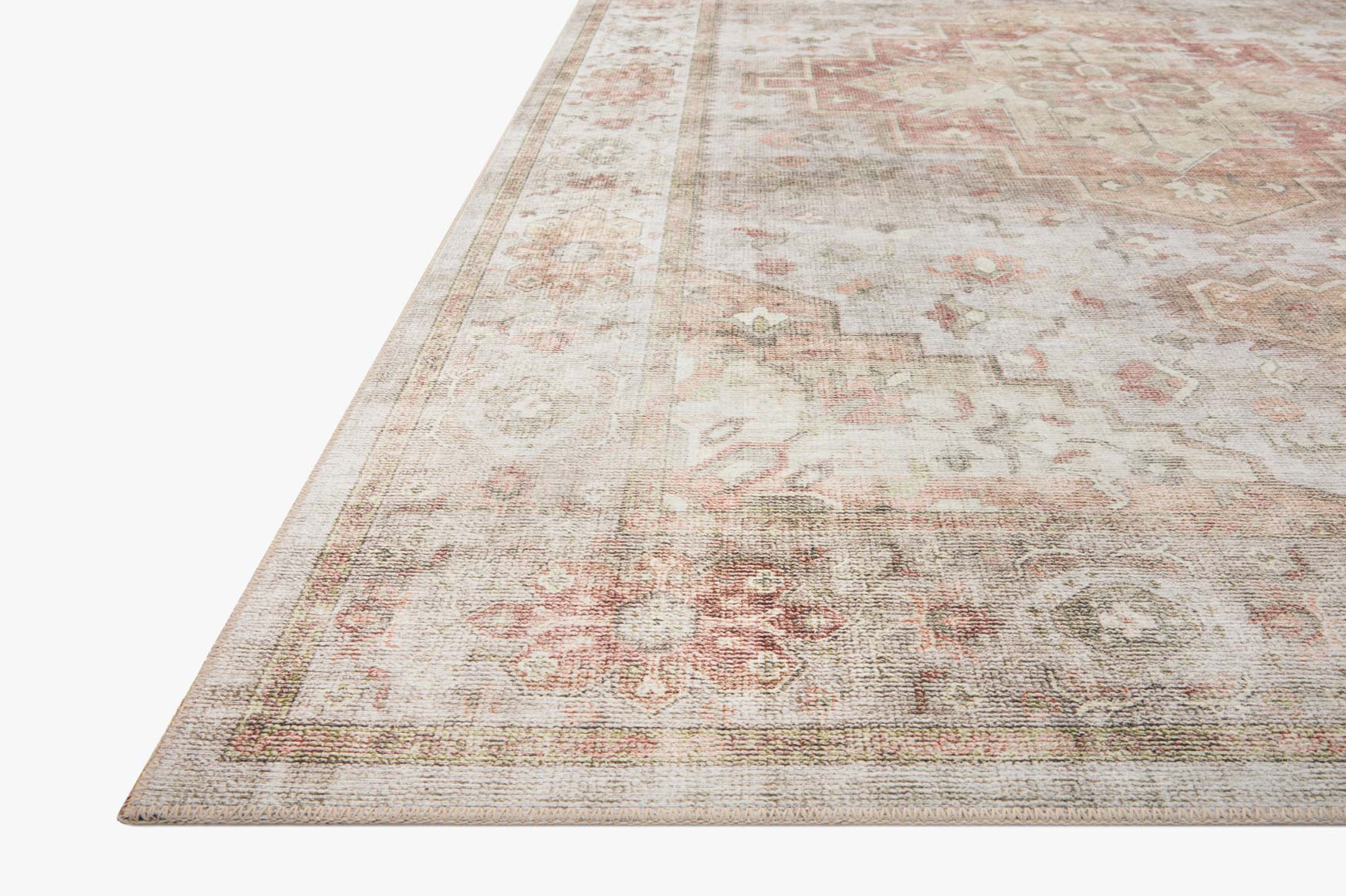 Traditional power-loomed rug corner view with distressed motifs in sage, beige, and rust